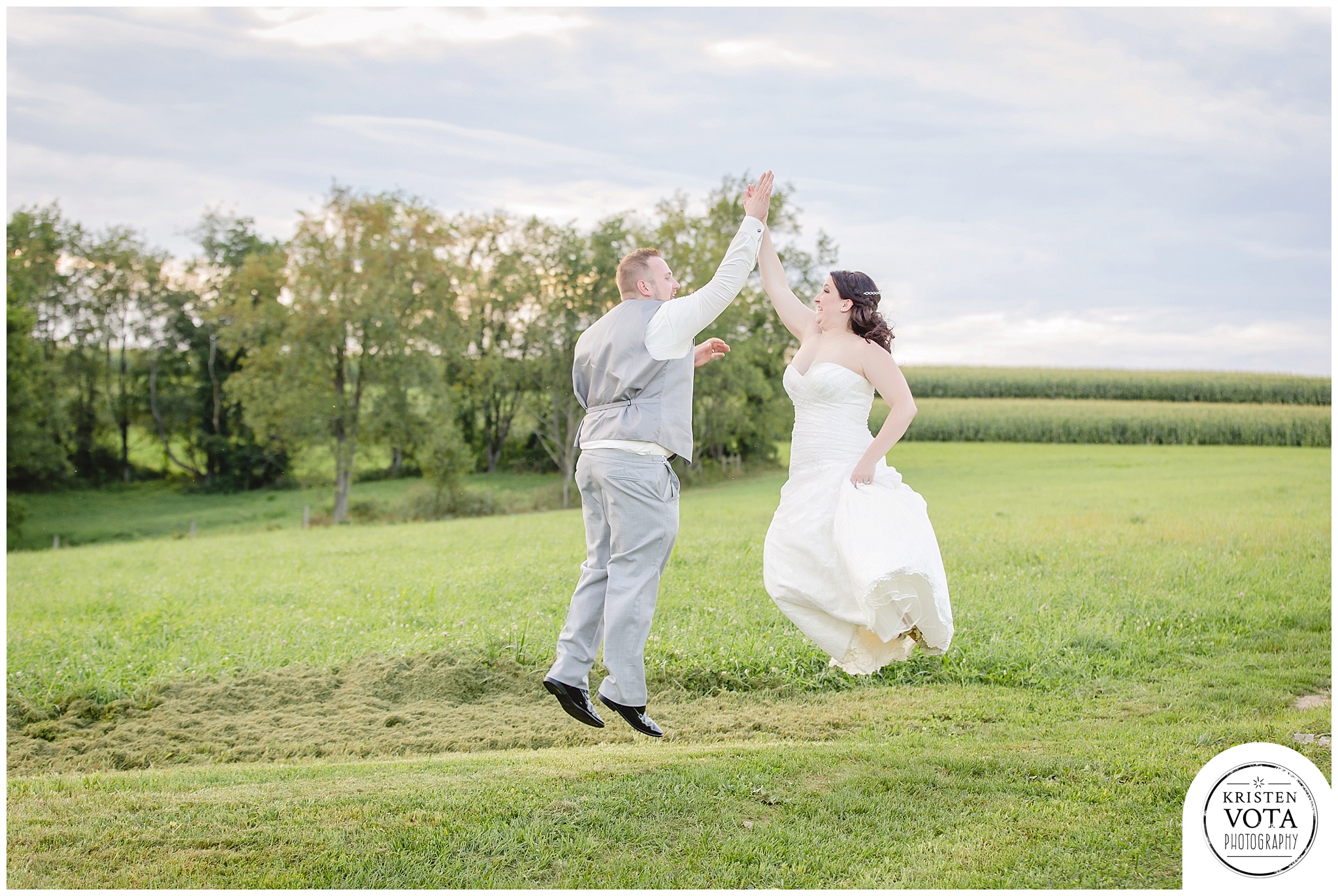 Newlyweds high-fiving at their rustic farm wedding in western Pennsylvania.