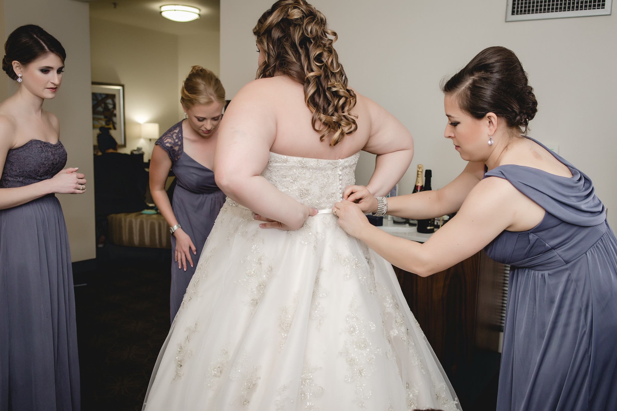Bridesmaids help bride into her dress before a Pittsburgh wedding at Soldiers & Sailors