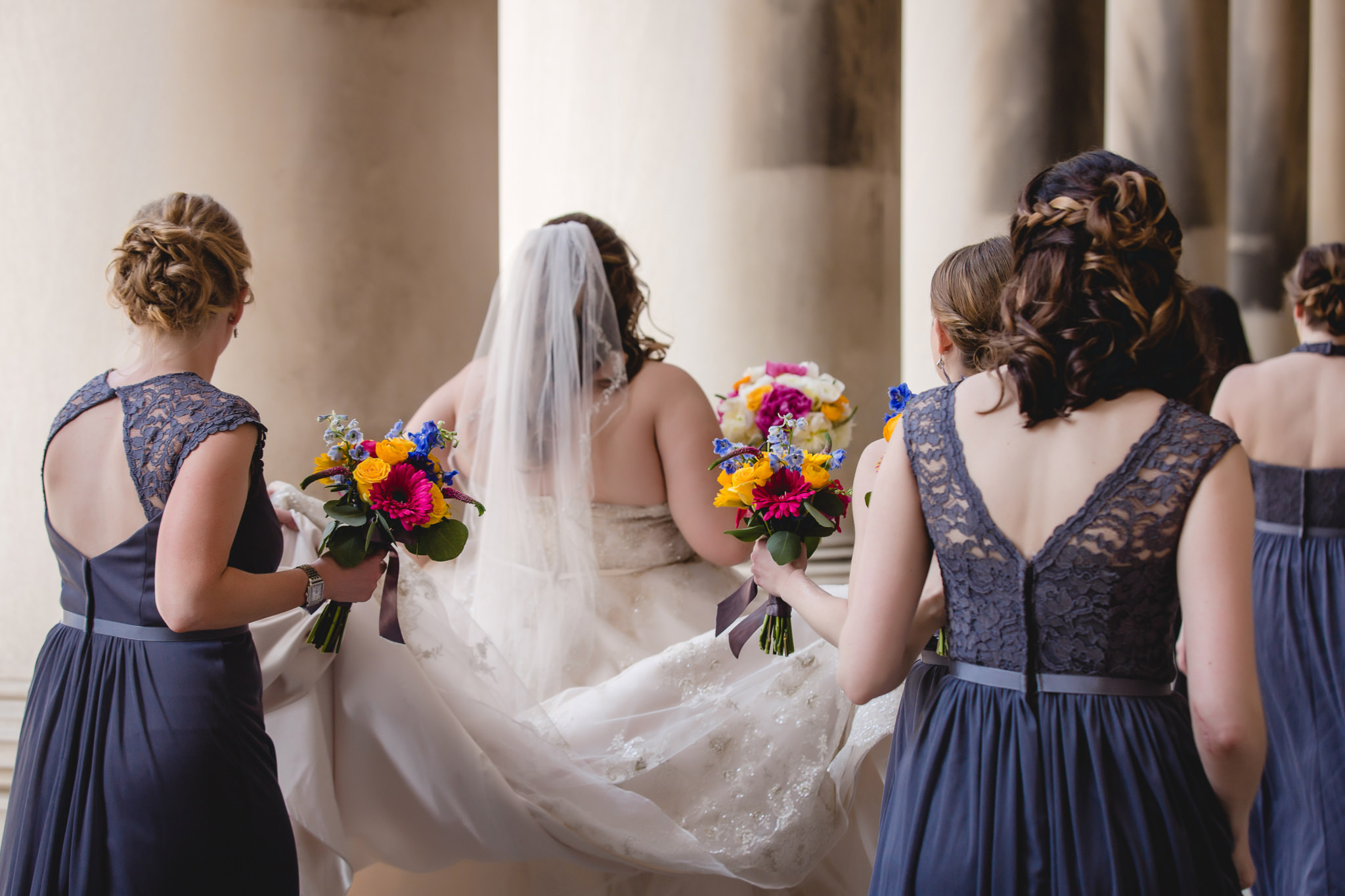 Bridesmaids help bride walk at the CMU columns in Oakland Pittsburgh
