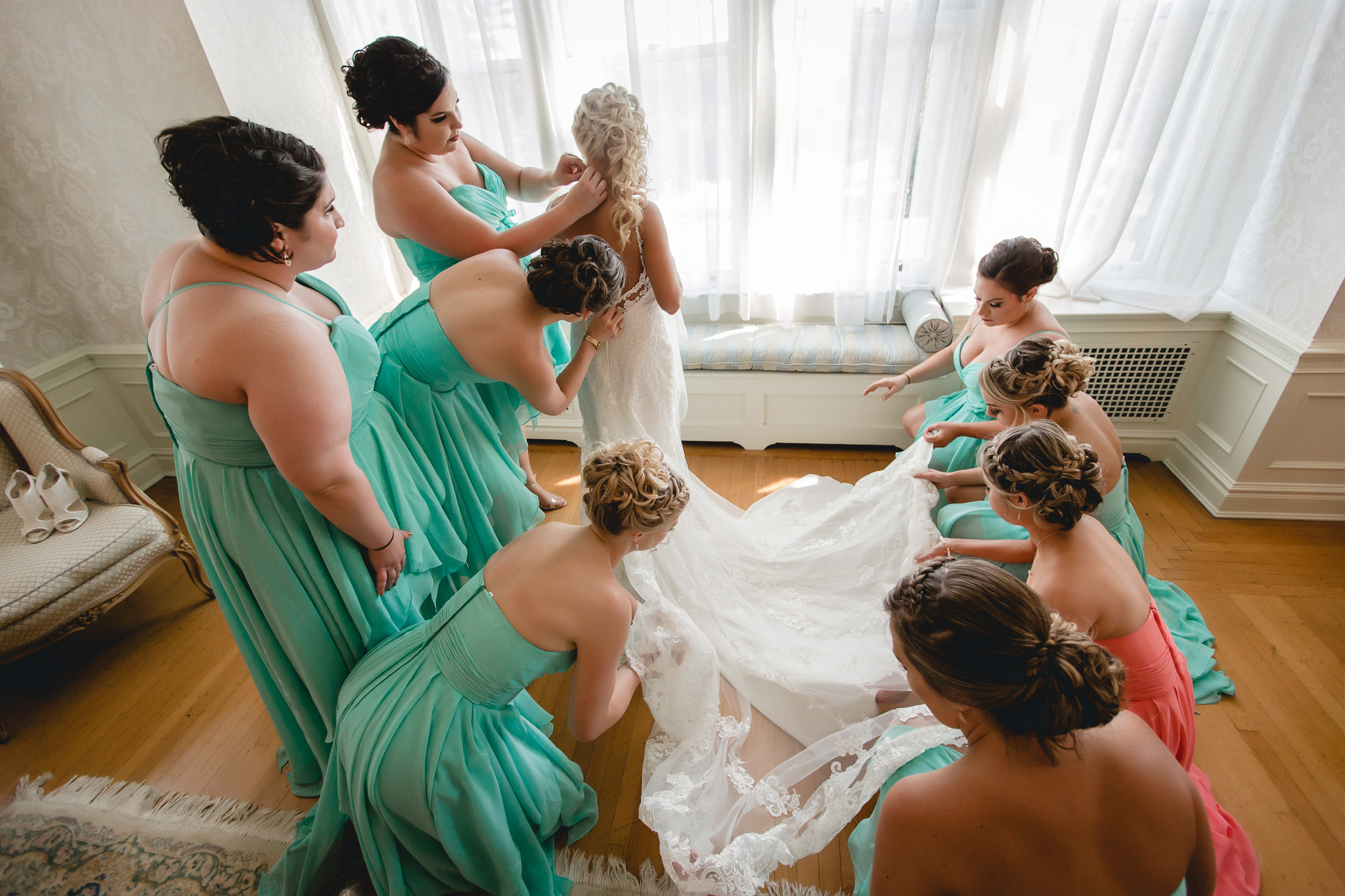 Bridesmaids help the bride put finishing touches on her wedding dress