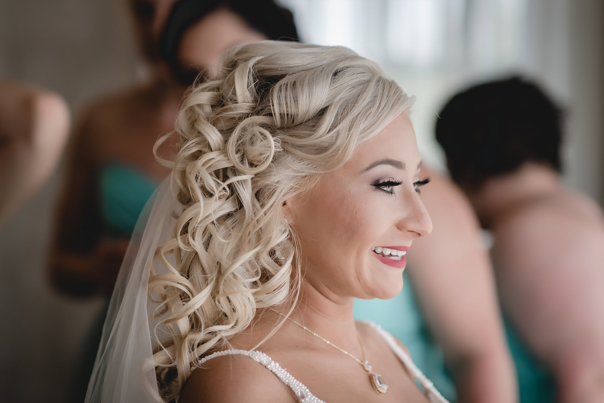 Side profile of bride's face while her bridesmaids help her get dressed