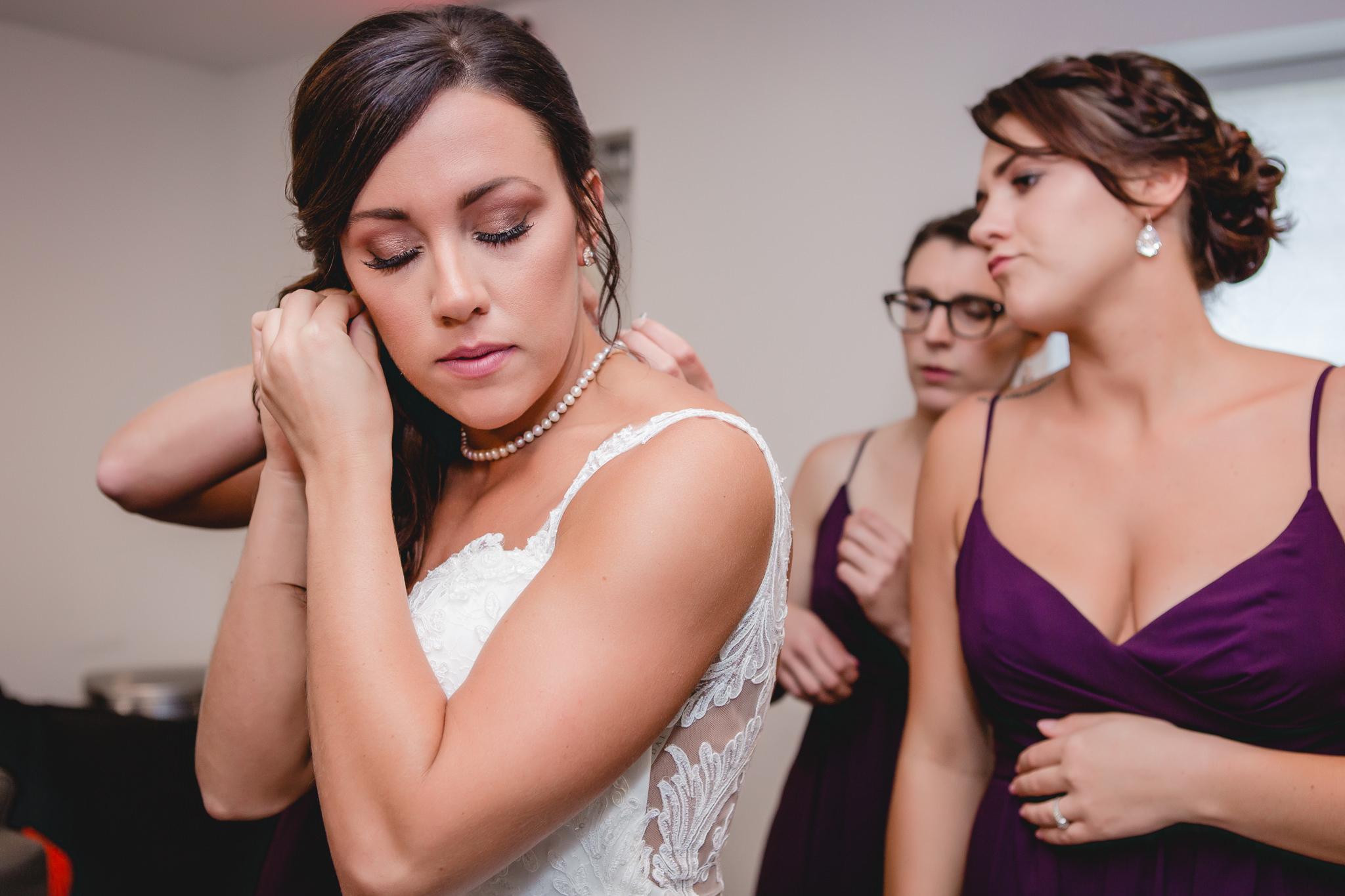 Bride puts in her earrings before her wedding ceremony at White Barn