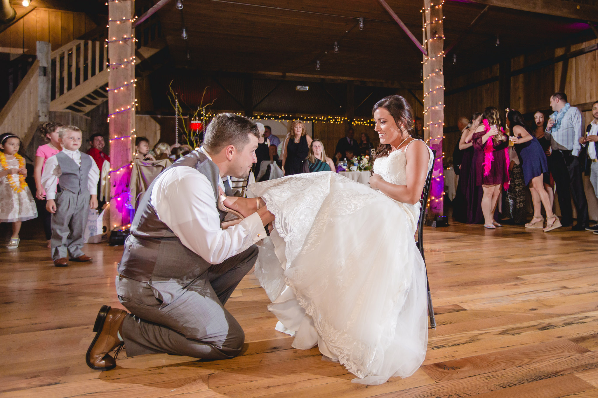 Groom removes the bride's garter at their White Barn wedding