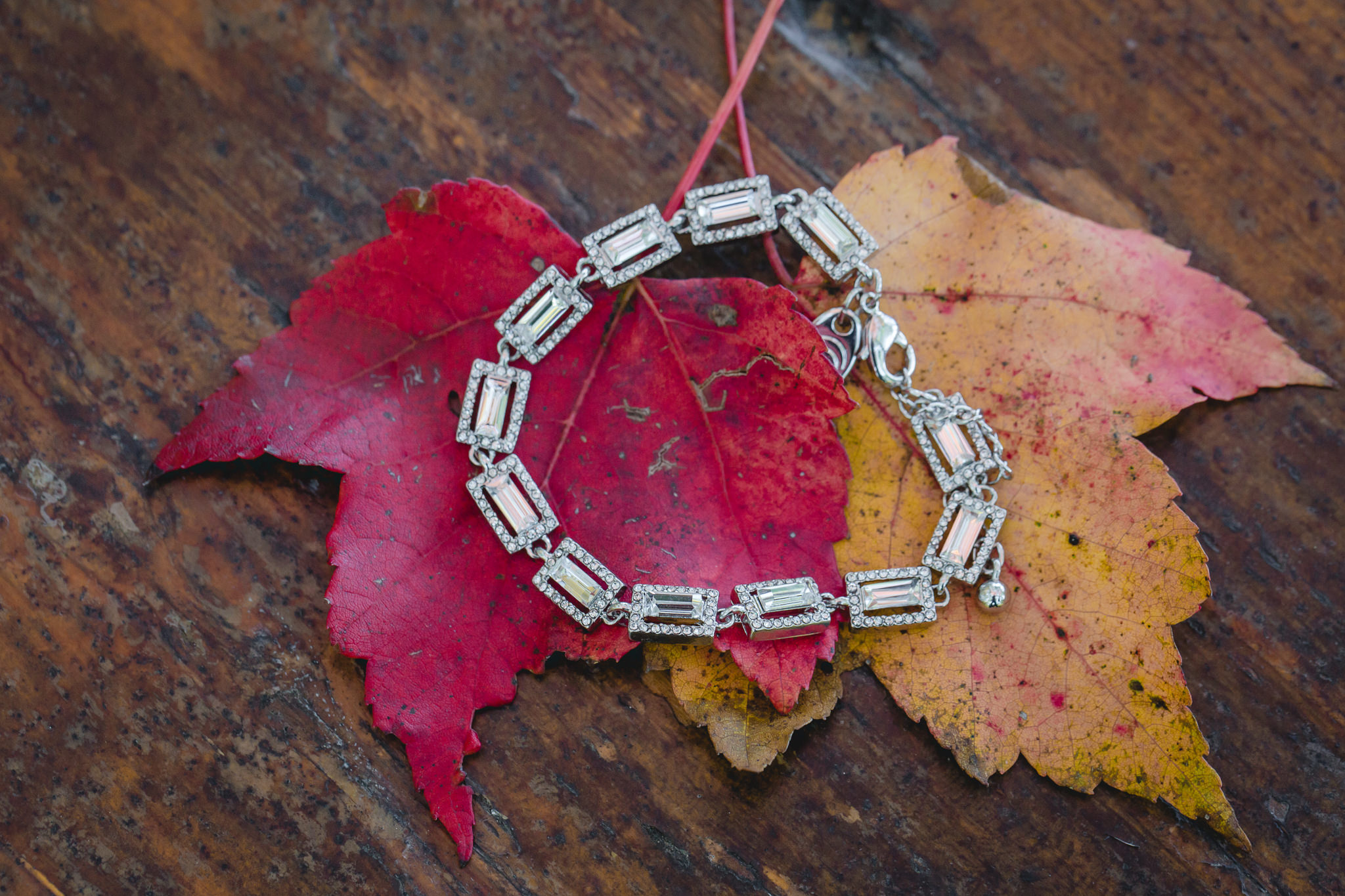 Bride's diamond bracelet rests on colorful fall leaves at the Barn at Soergel Hollow
