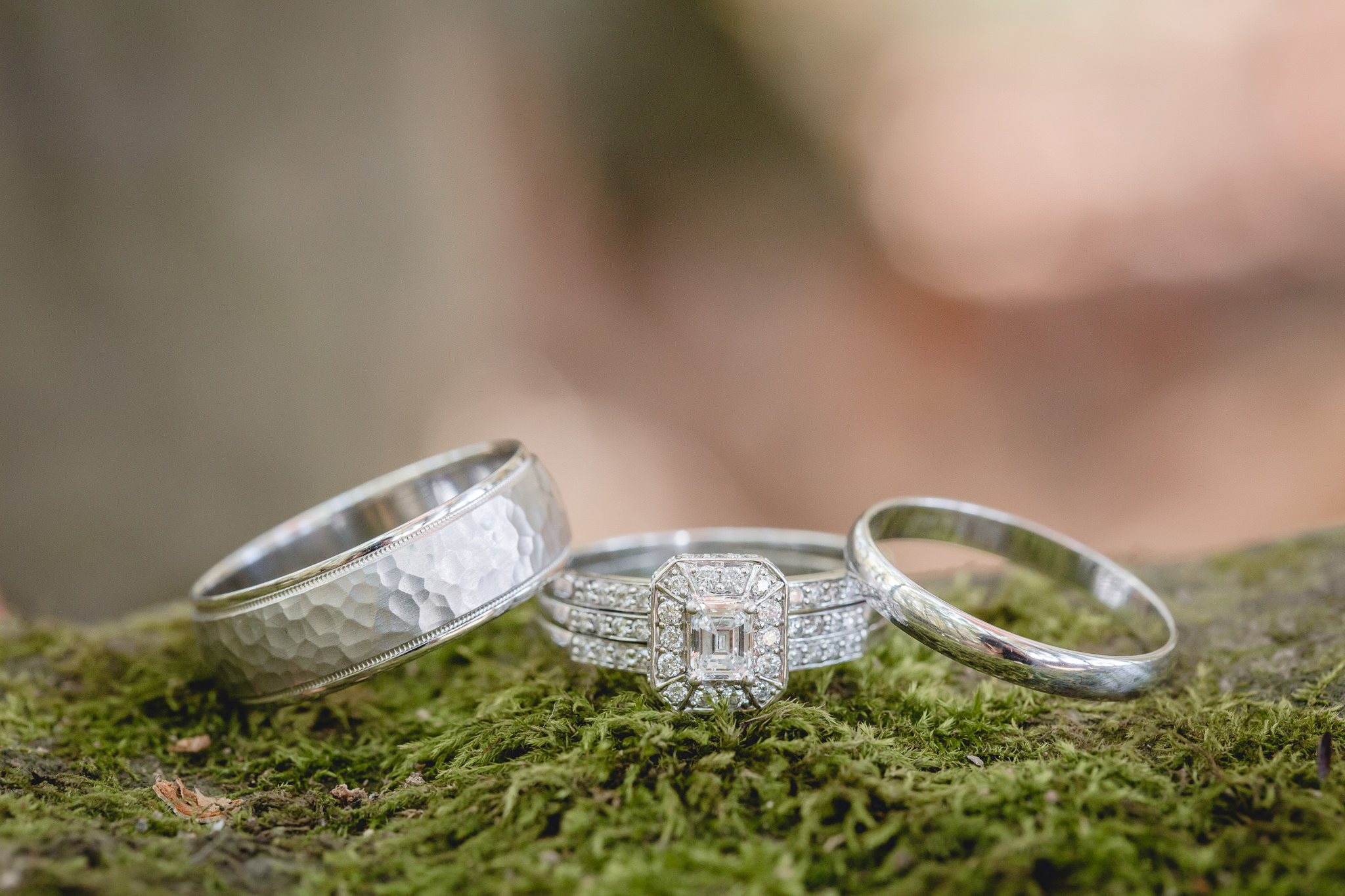 Engagement ring and wedding bands rest on moss at the Barn at Soergel Hollow