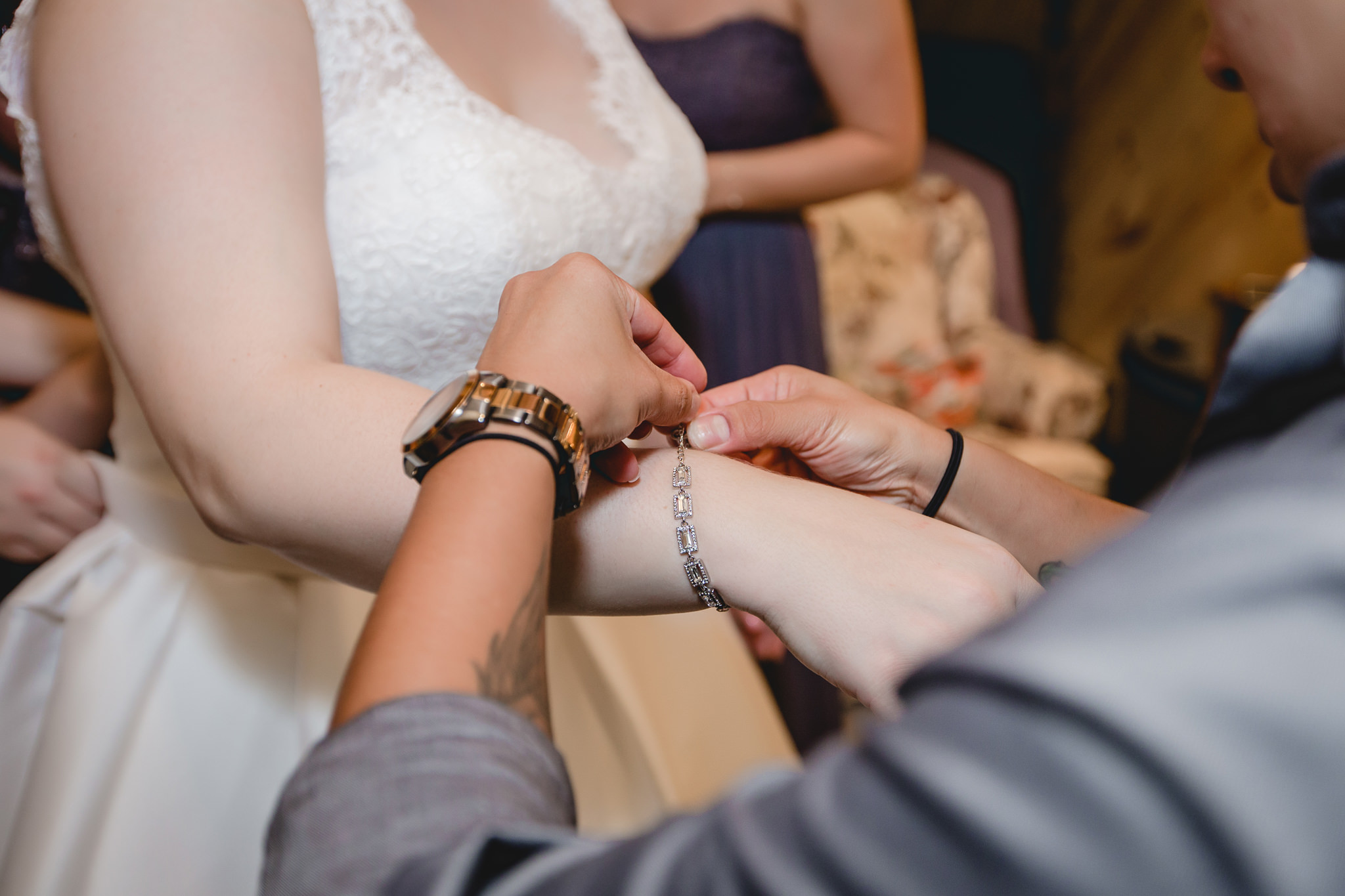 Bridesmaid puts the bride's diamond bracelet on her wrist