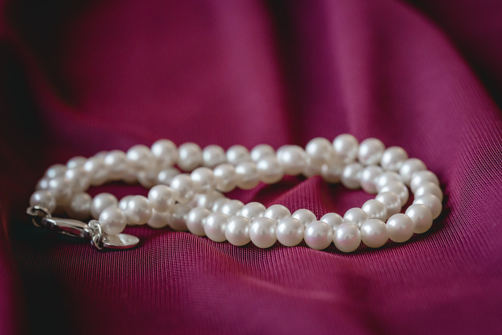 Bride's white pearl necklace against a wine colored bridesmaids dress