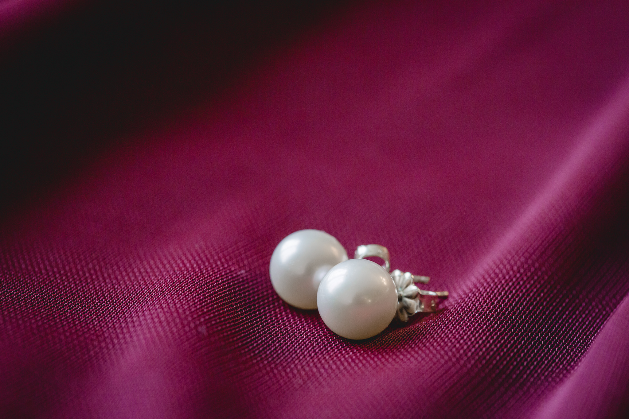 Bride's white pearl earrings on a wine colored bridesmaids dress