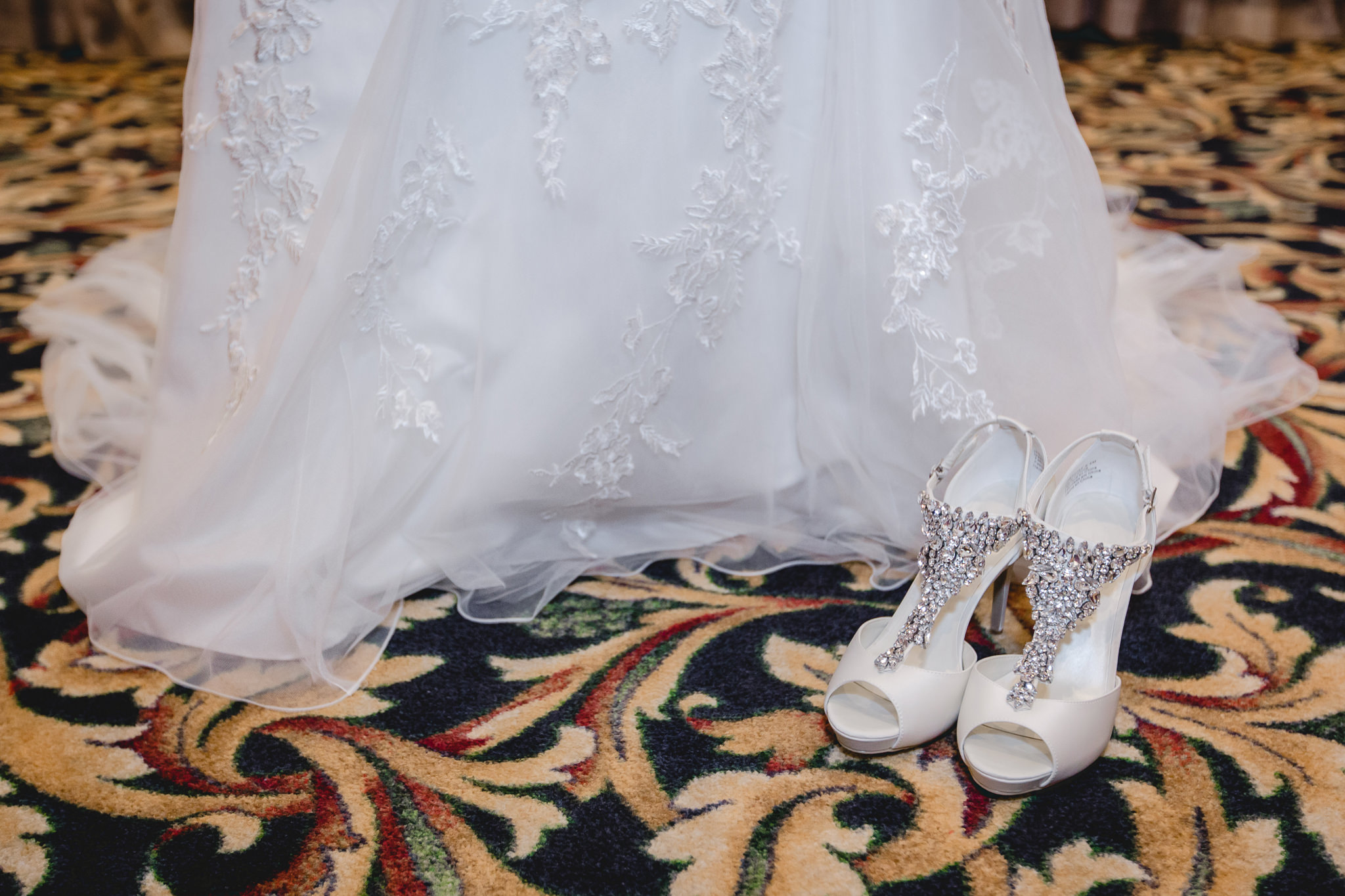 Bride's white sparkling heels rest next to her wedding gown at the Chadwick