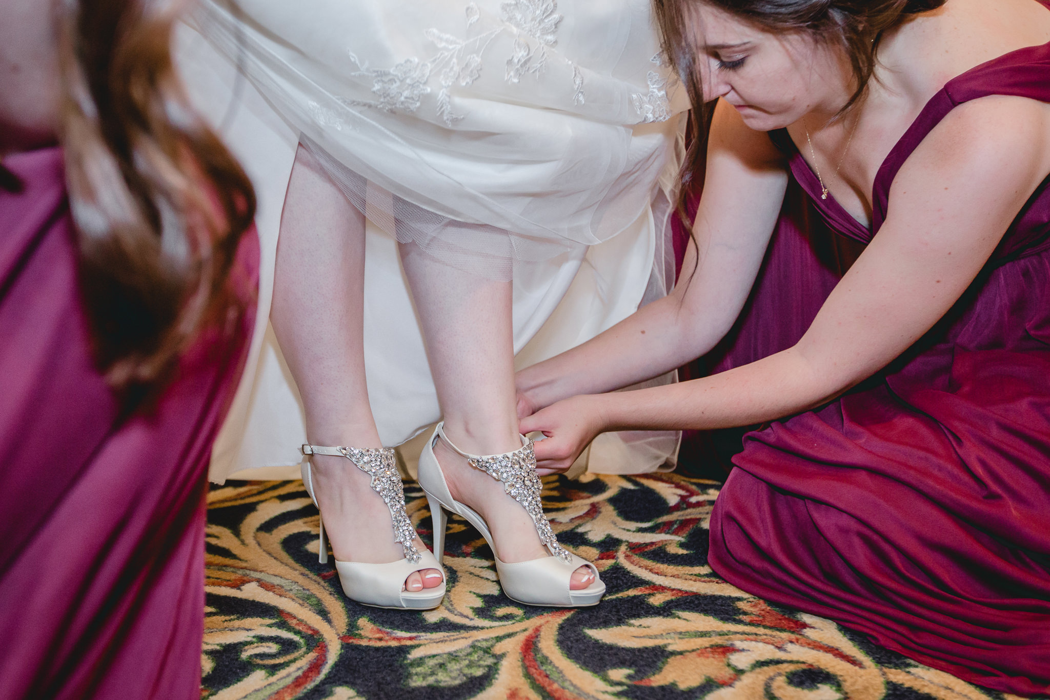 Bridesmaids help the bride into her shoes at the Chadwick