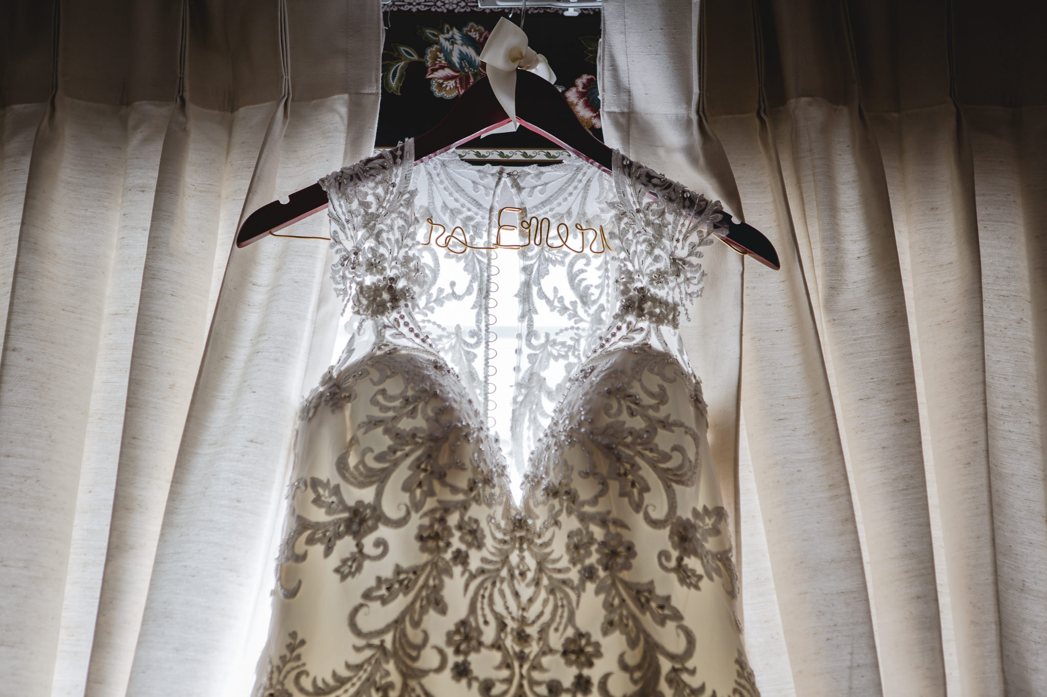 Lace detailed wedding dress hangs on a custom hanger