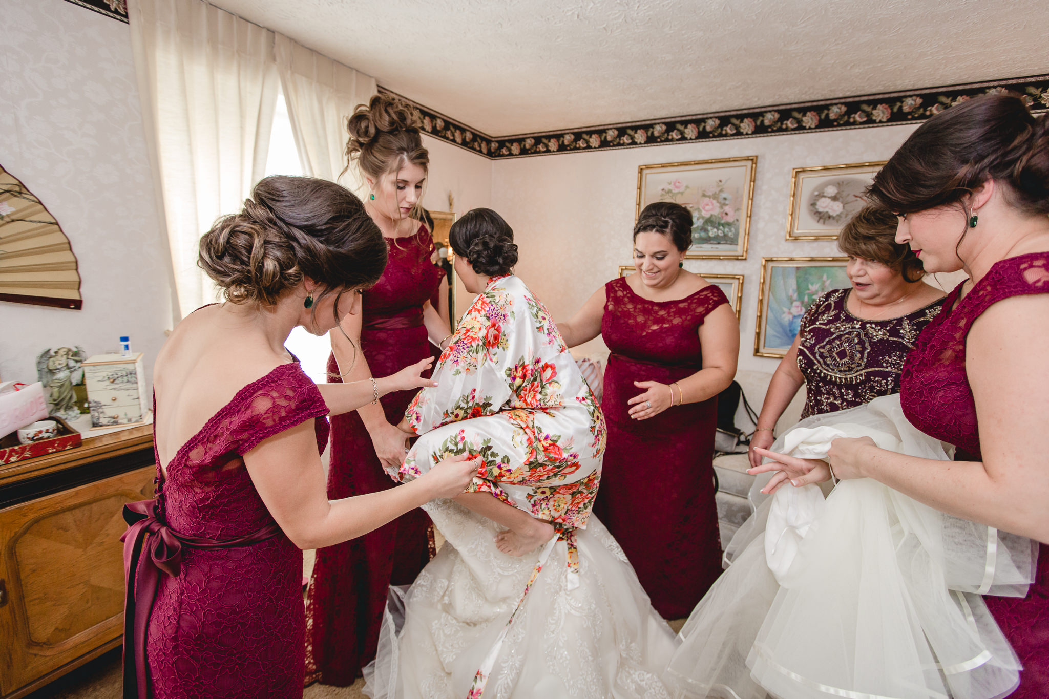 Bridesmaids help bride into her dress before her DoubleTree Pittsburgh Airport wedding
