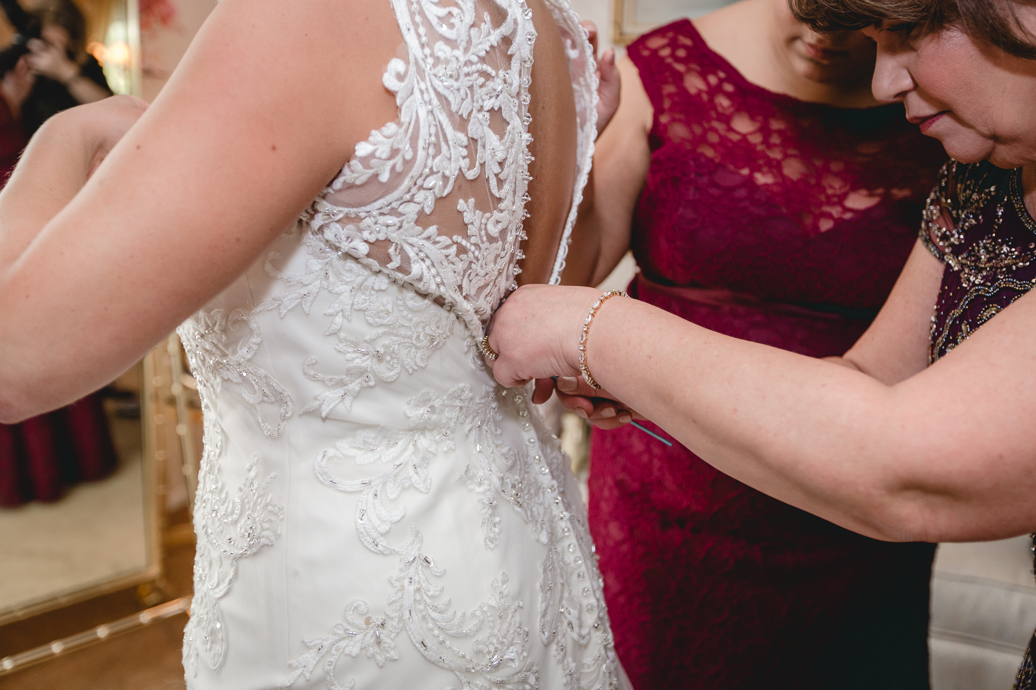 Mother of the bride zips the bride's vintage style wedding dress