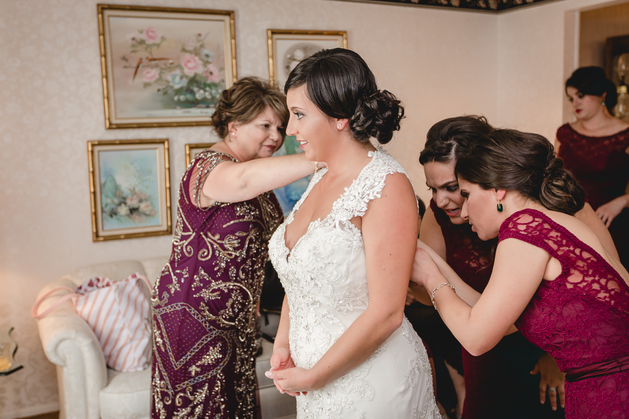 Bridesmaids help with the bride's dress before her DoubleTree Pittsburgh Airport wedding