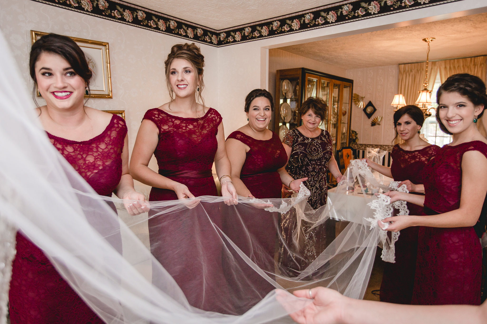 Bridesmaids hold the bride's veil while she gets ready for her October wedding