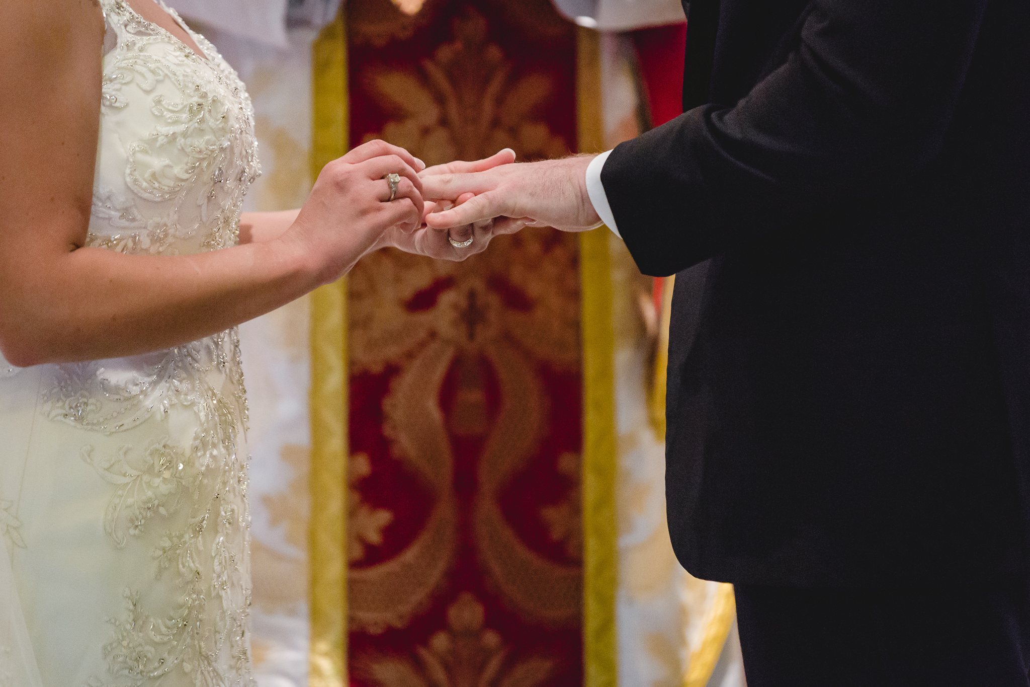 Bride places groom's wedding band on his finger at St. John the Baptist