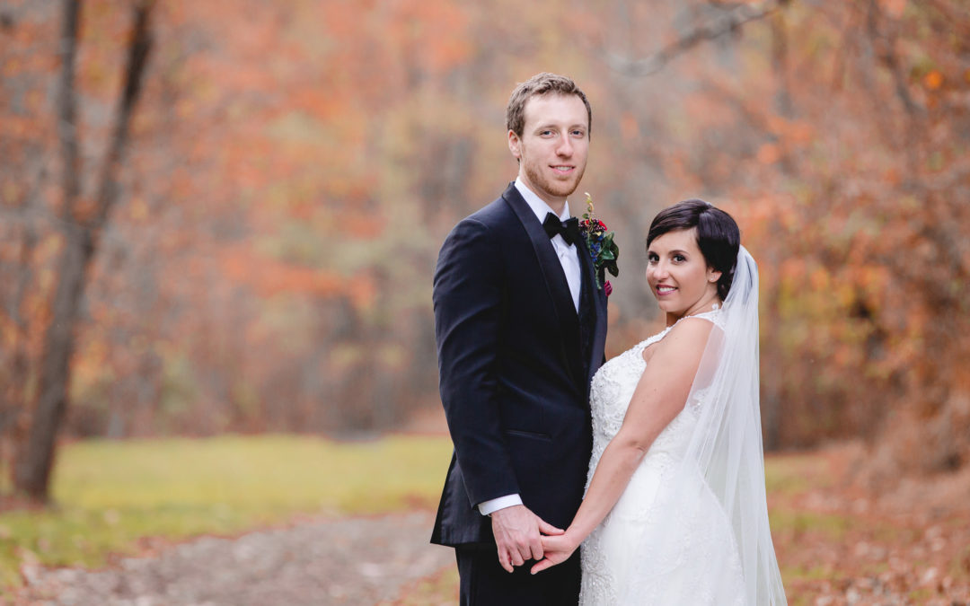 Bride and groom hold hands in a park with fall foliage before their wedding at DoubleTree Pittsburgh Airport