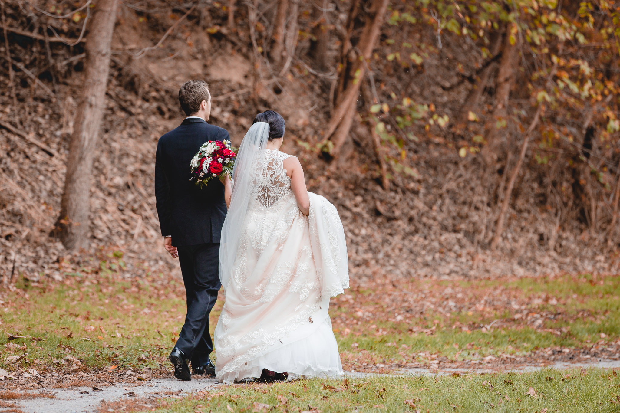 Newlyweds walk down a path in the park before their DoubleTree Pittsburgh Airport wedding reception