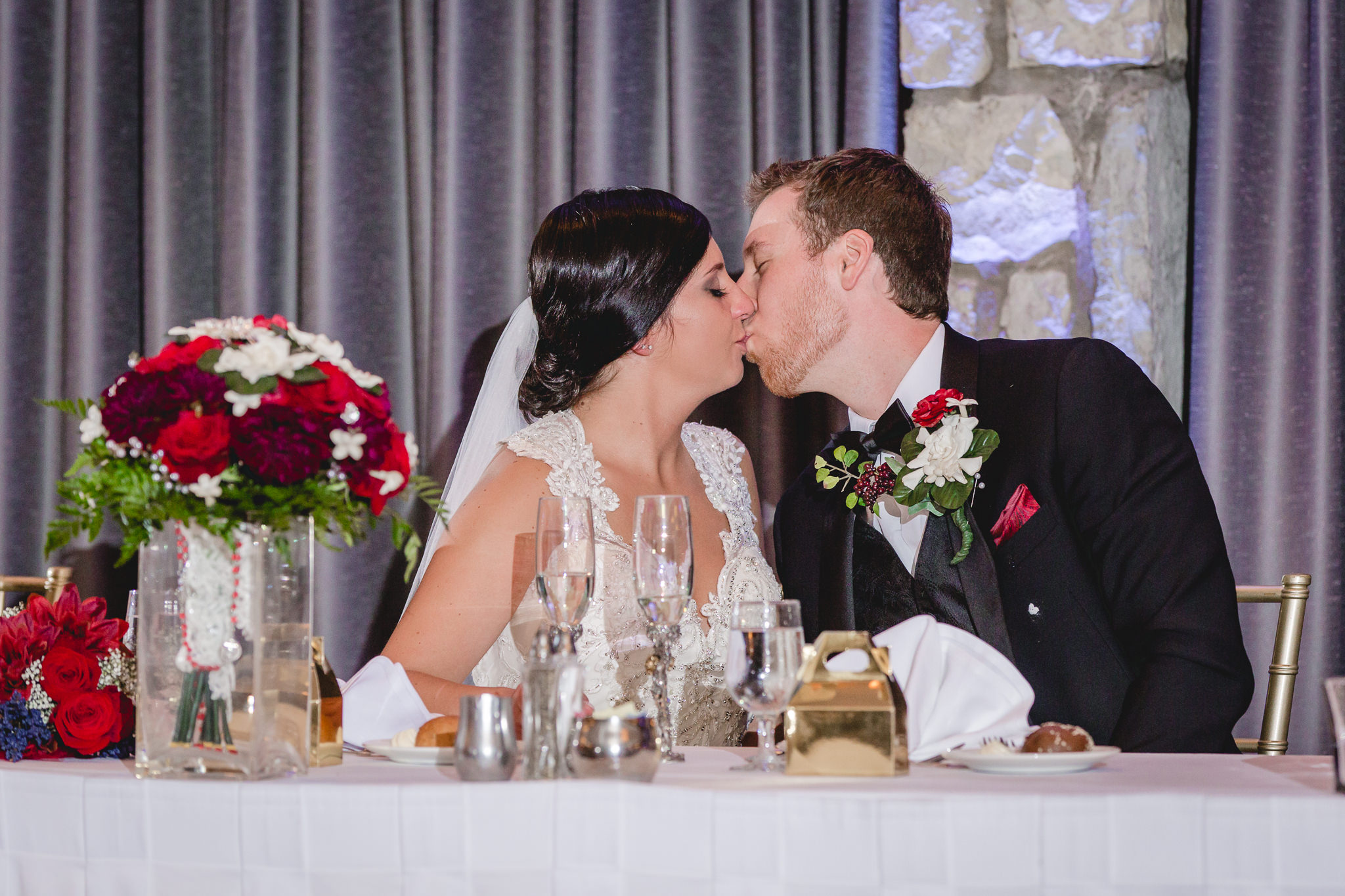 Bride and groom kiss at the head table at the DoubleTree Pittsburgh Airport