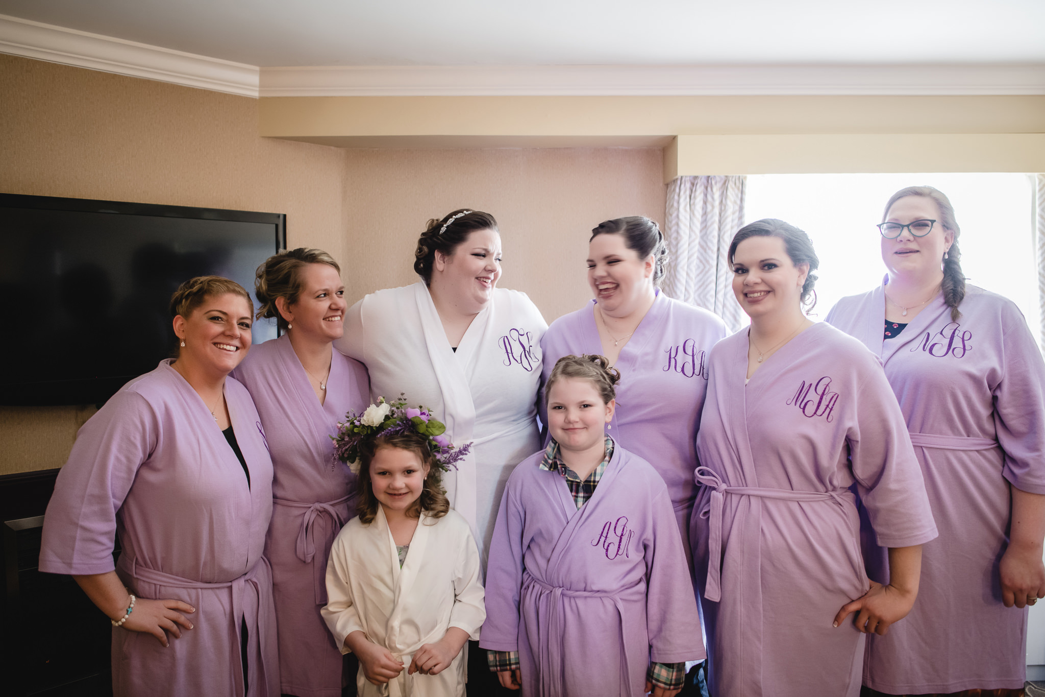 Bride laughs with her bridesmaids in their custom monogram robes