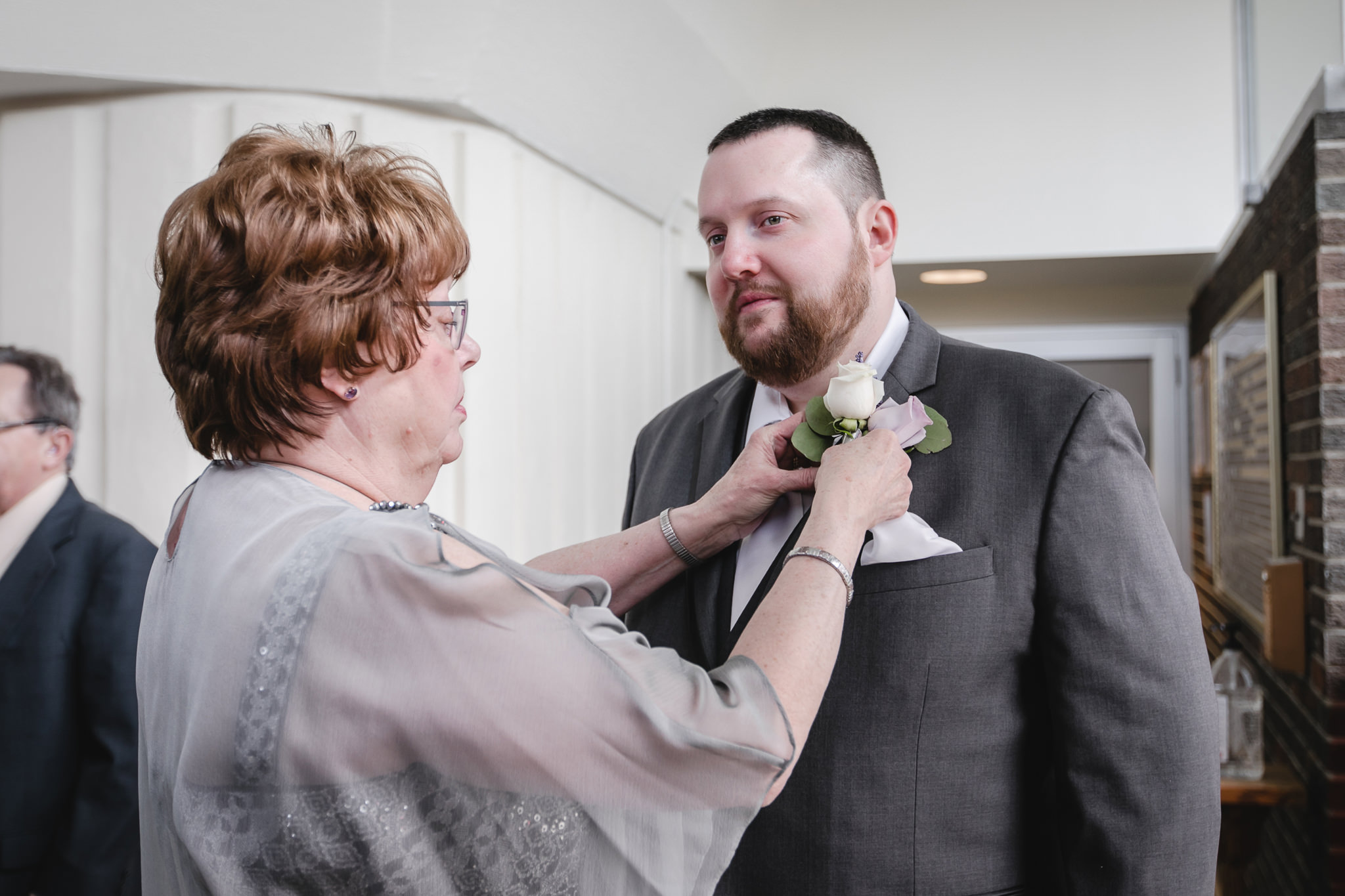 Mother of the groom pins on his boutonniere before his wedding at Holy Trinity in Robinson