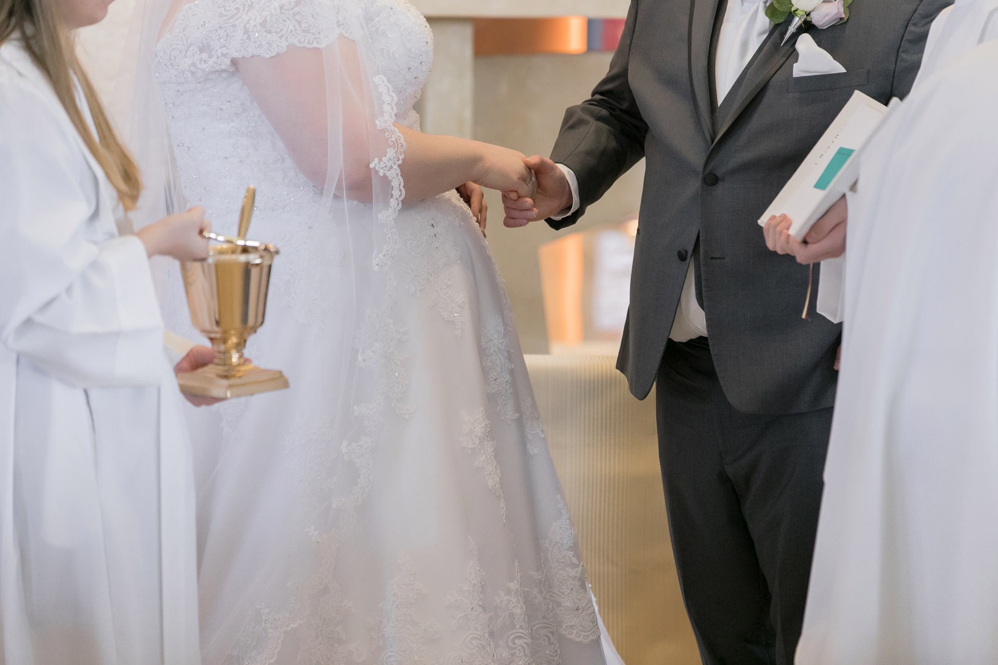 Bride and groom hold hands during their Holy Trinity wedding ceremony