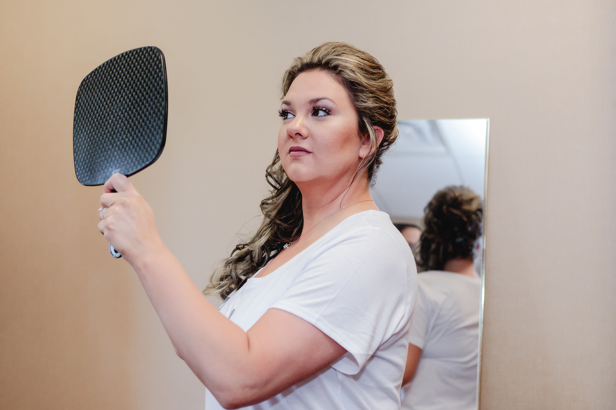 Bride checks her hair in the mirror before her Chestnut Ridge Golf Resort wedding ceremony