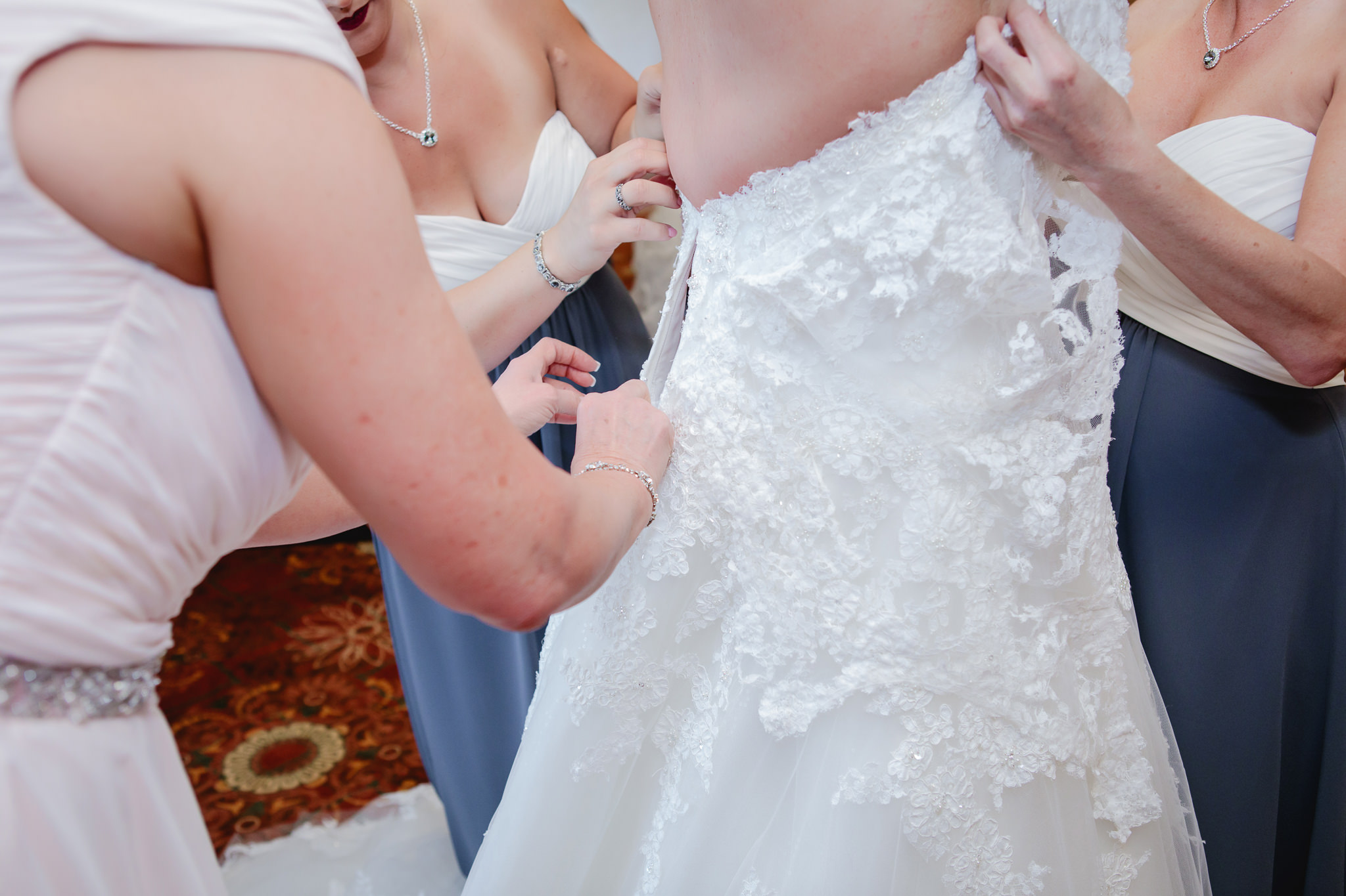 Bridesmaids help bride into her dress at Chestnut Ridge Golf Resort