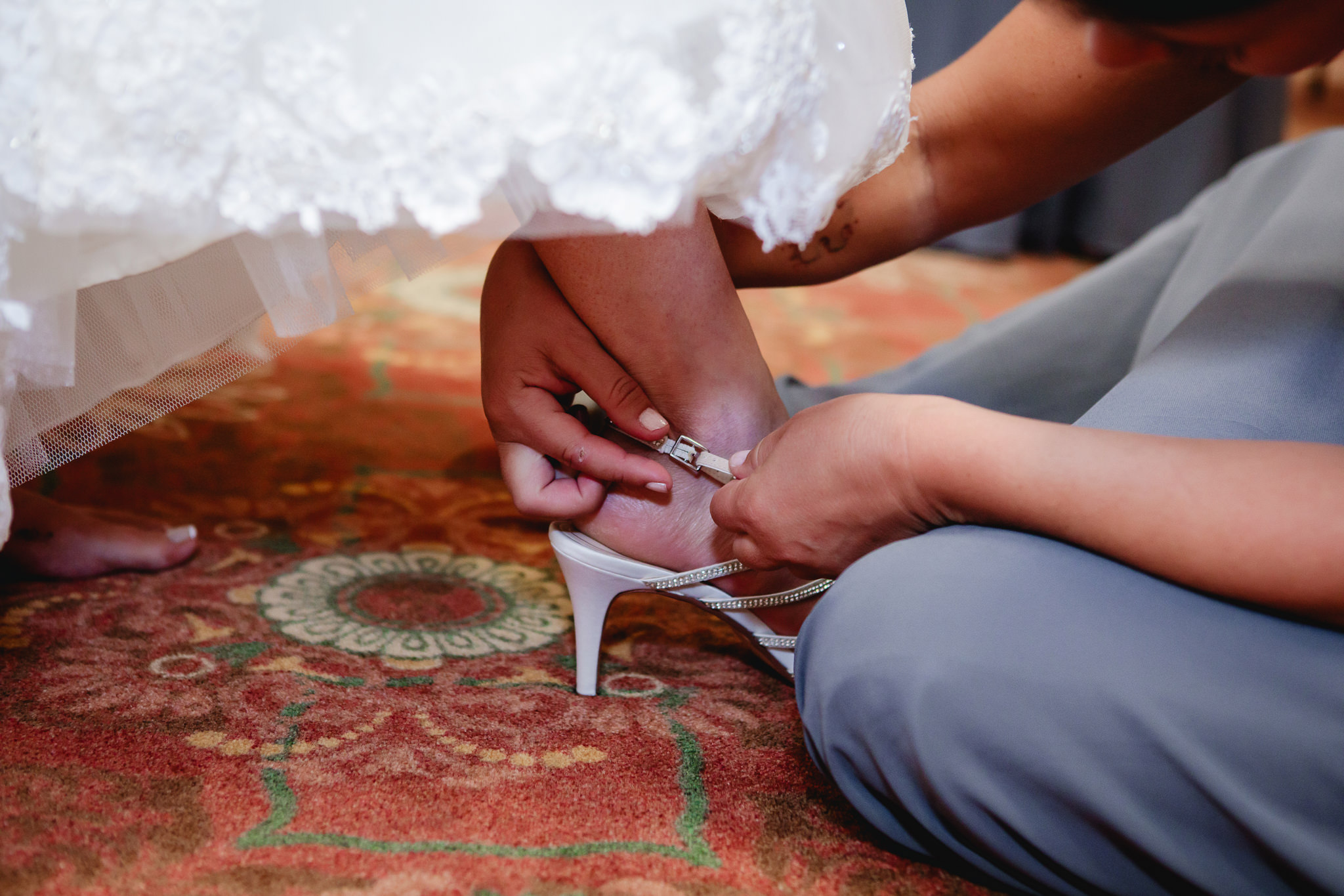Bride's sister-in-law helps with her wedding shoes