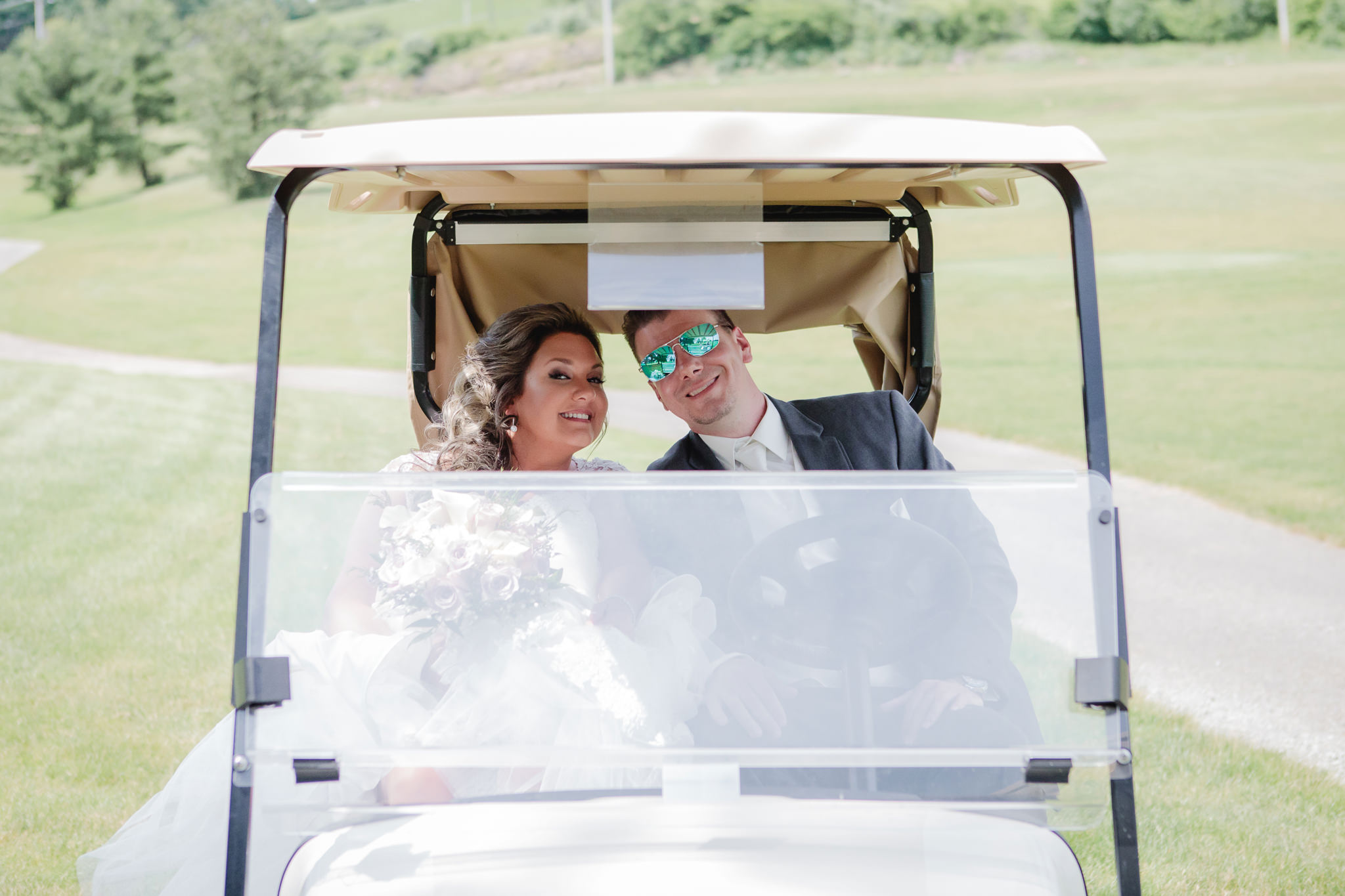 Bride & groom ride in a golf cart at Chestnut Ridge Golf Resort