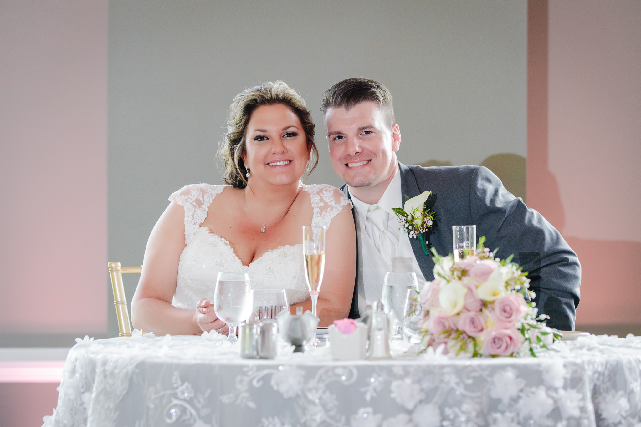 Bride and groom pose for a photo at their sweetheart table
