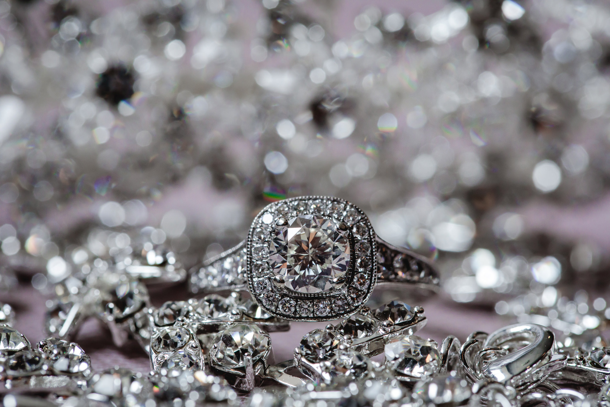 Diamond engagement ring rests on bride's diamond jewelry
