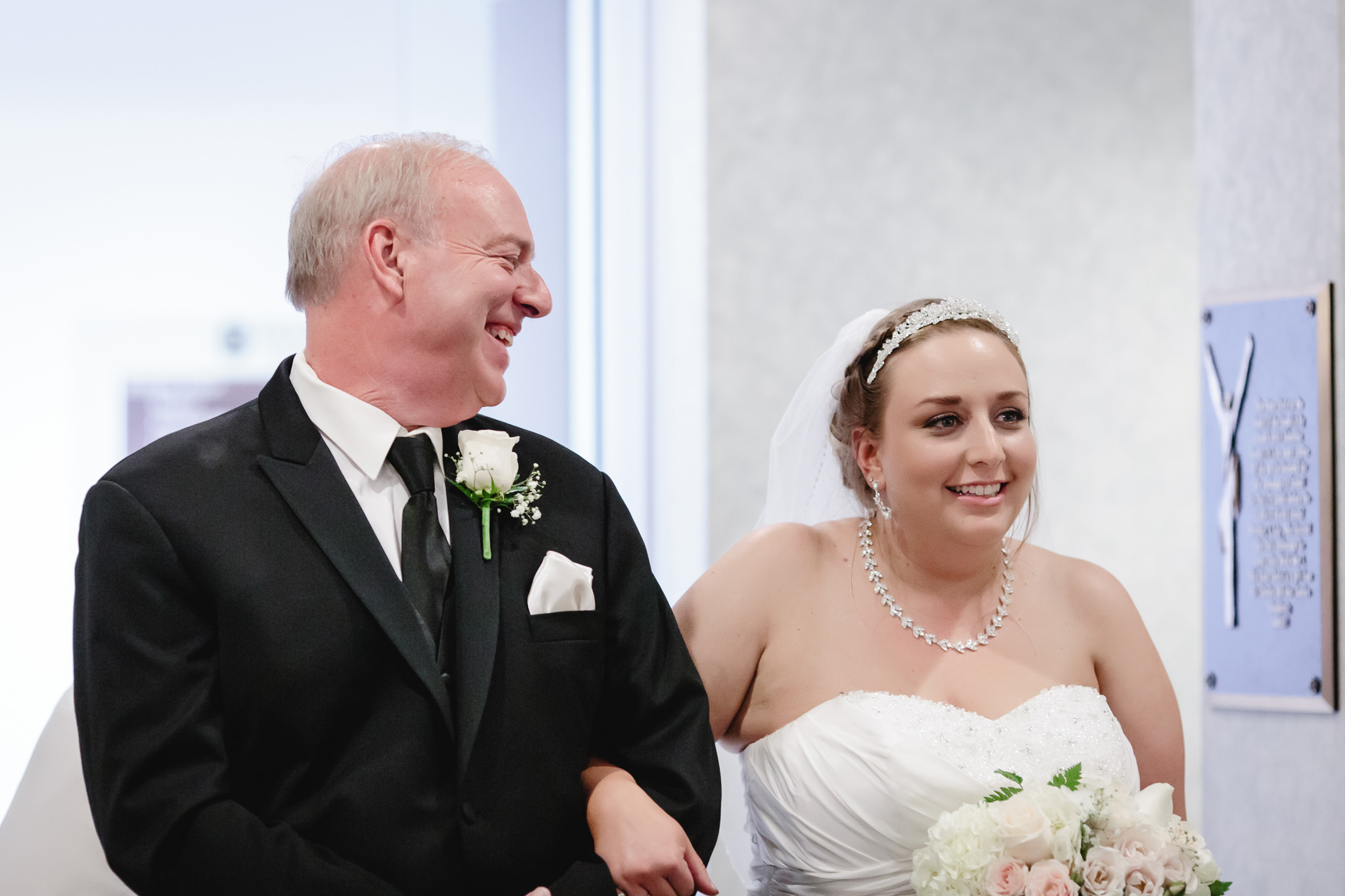 Father of the bride smiles at his daughter before walking down the aisle