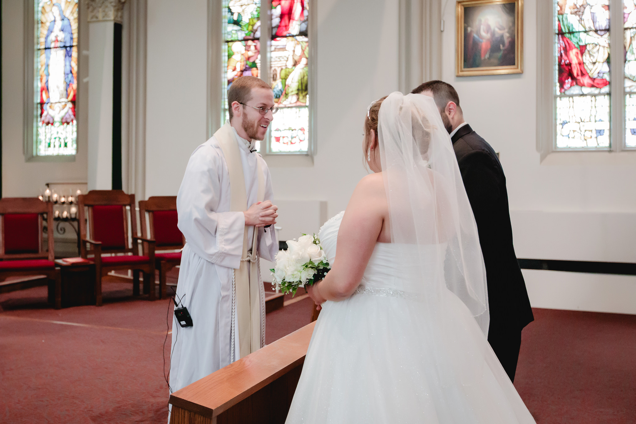 Priest greets the bride and groom at Duquesne University's Chapel of the Holy Spirit