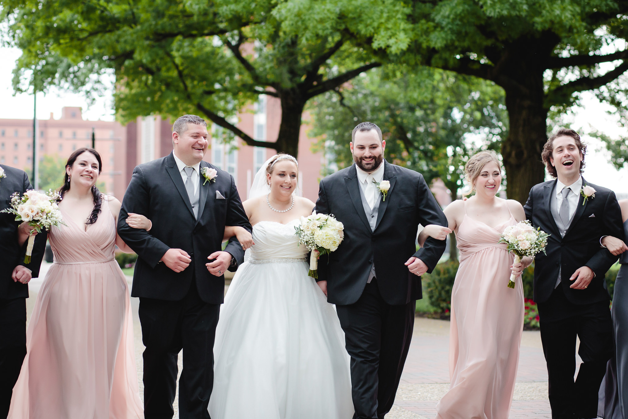 Bride & groom walk and laugh with their bridal party on Academic Walk at Duquesne University