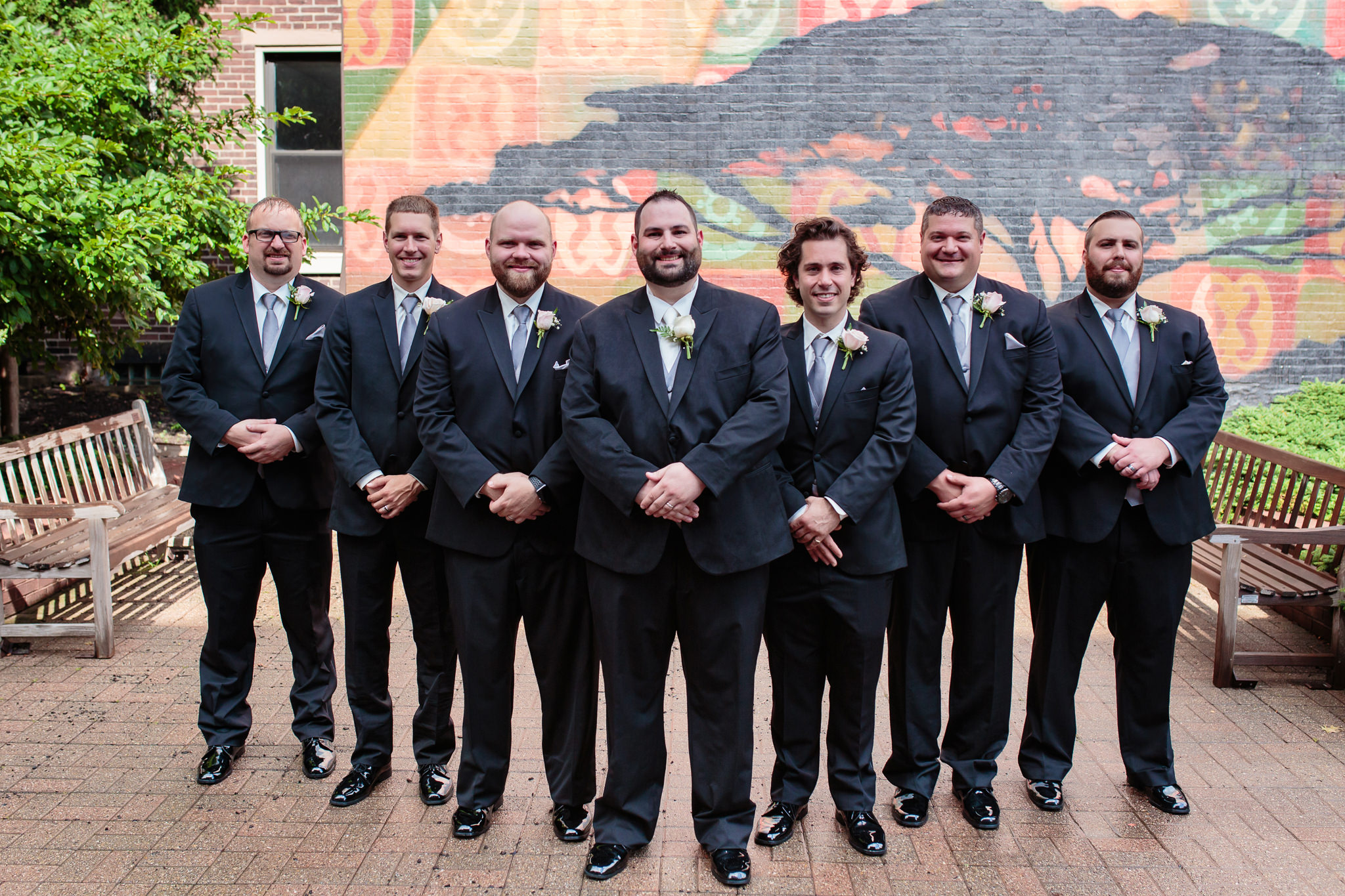 Groomsmen in front of wall mural at Duquesne University