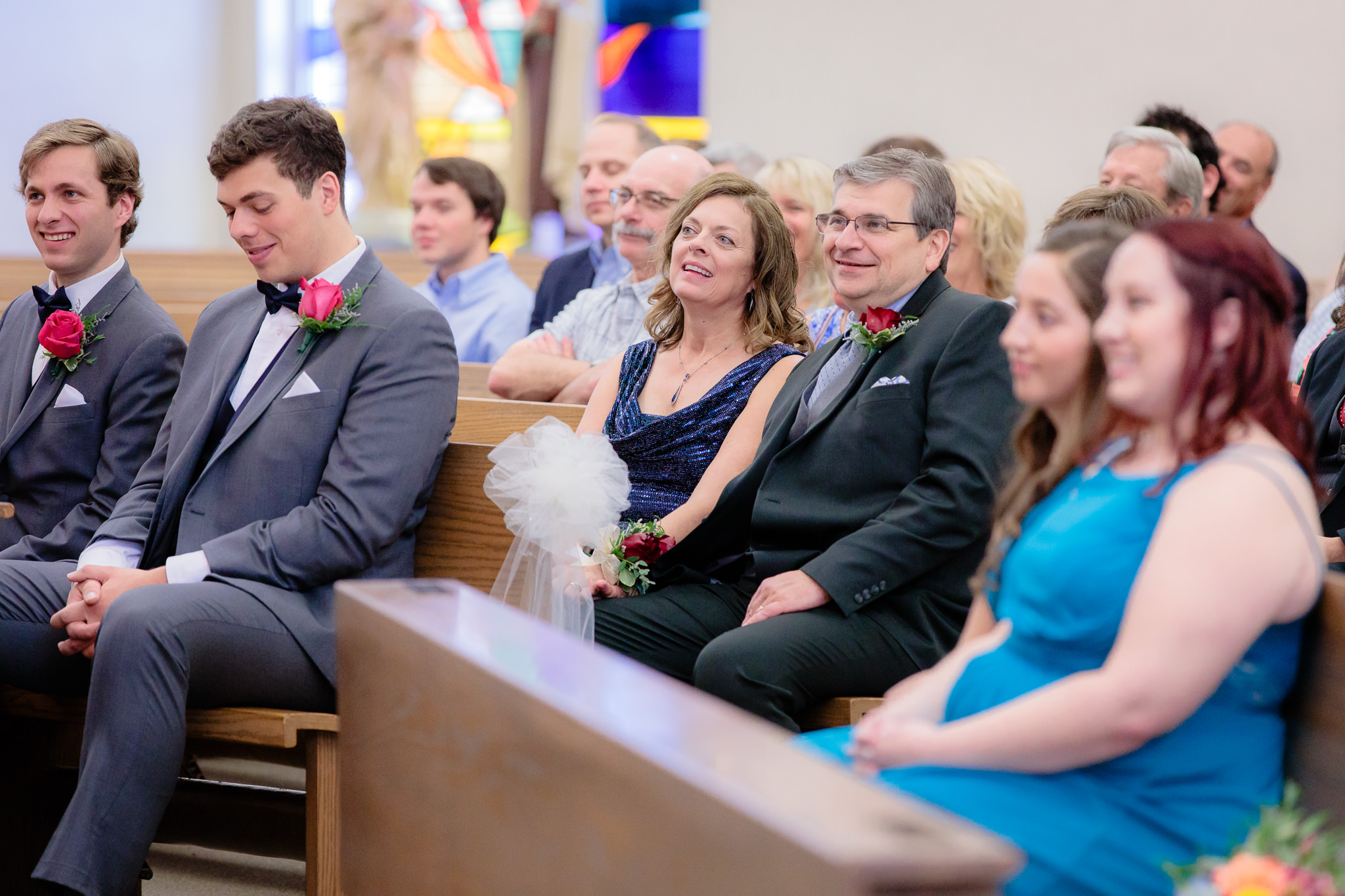Parents of the groom smile during a Saint Monica Parish wedding ceremony