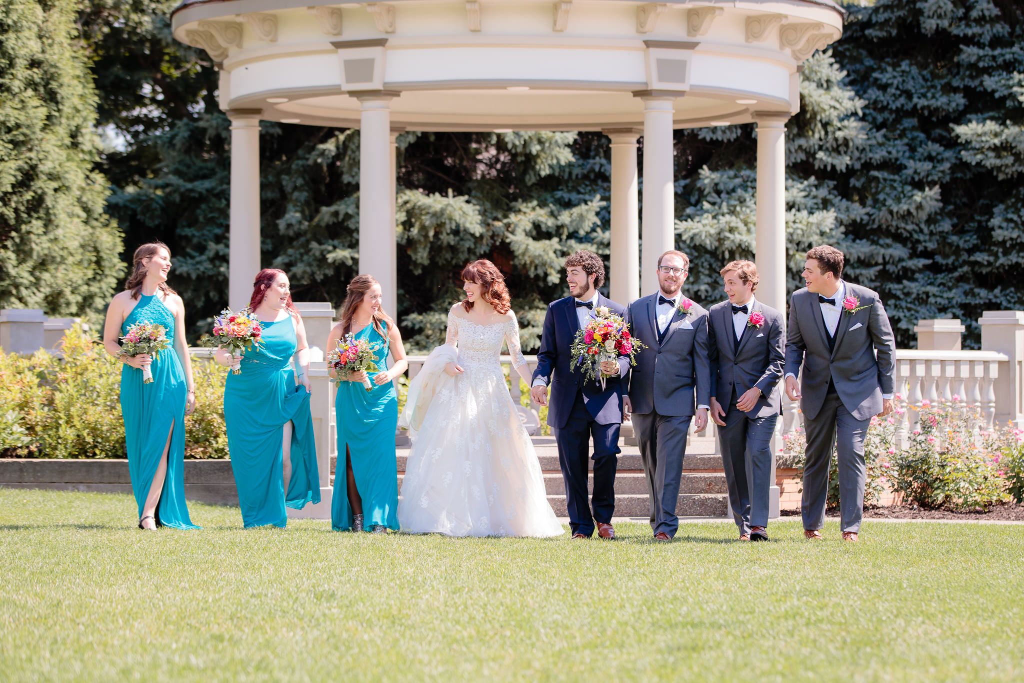 Bridal party walks and laughs in front of the gazebo at Beaver Station