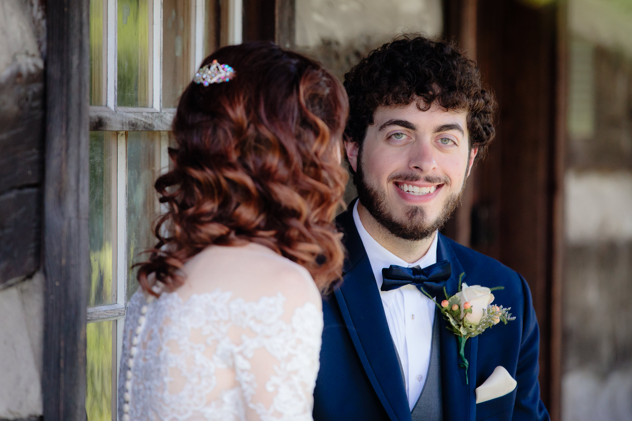 Groom smiles on the porch of a cabin at Beaver Station