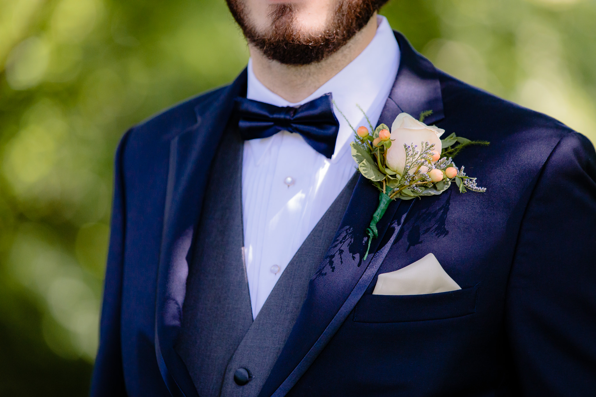 White rose boutonniere by Patti's Petals Flower Shop on a navy Joseph Abboud tuxedo from Men's Wearhouse