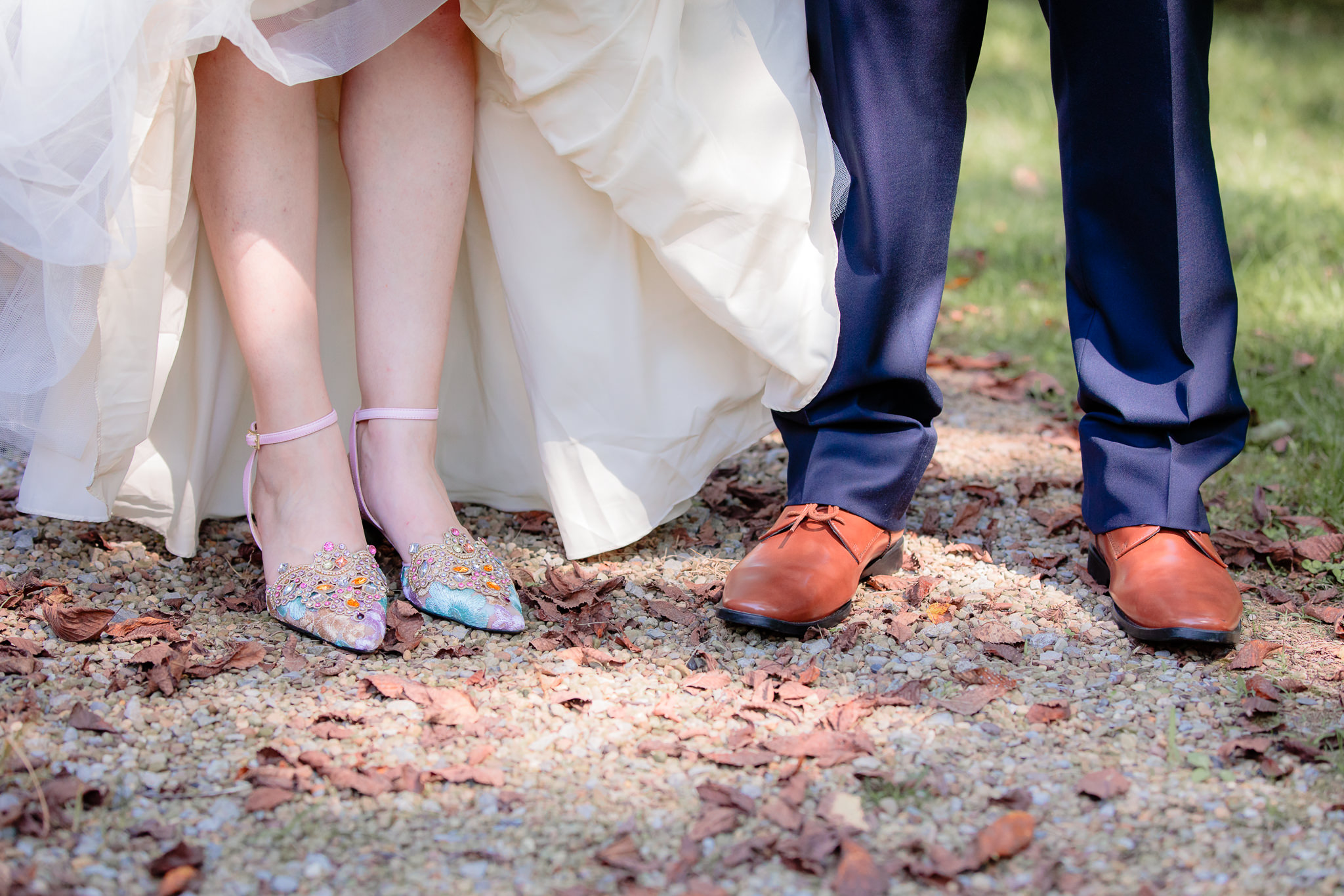 Bride's colorful jeweled shoes next to the groom's brown shoes and navy pants