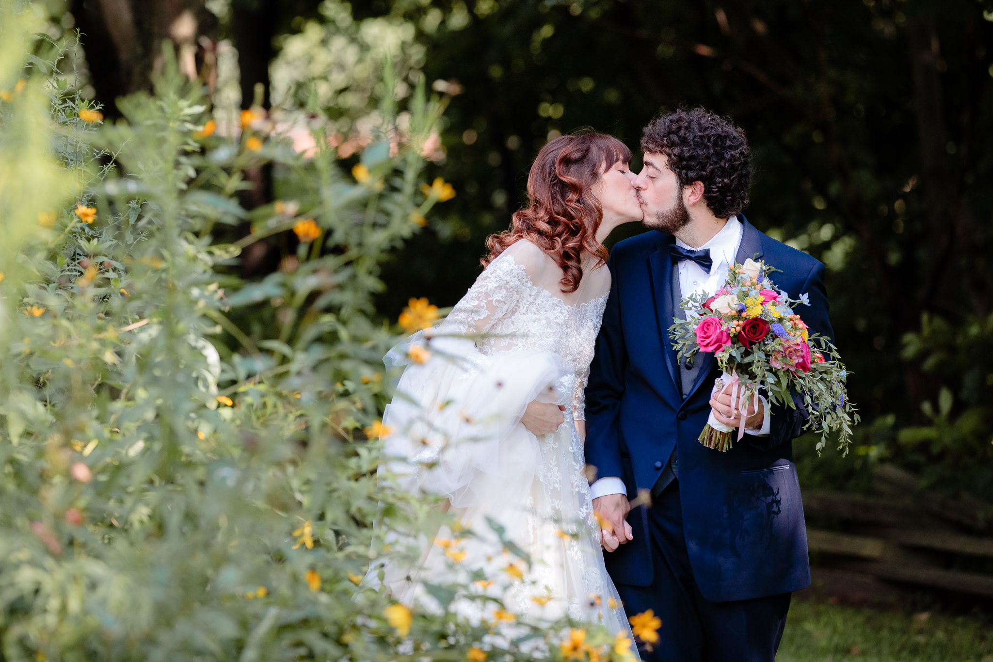 Newlyweds kiss in the flowers on the grounds of Beaver Station