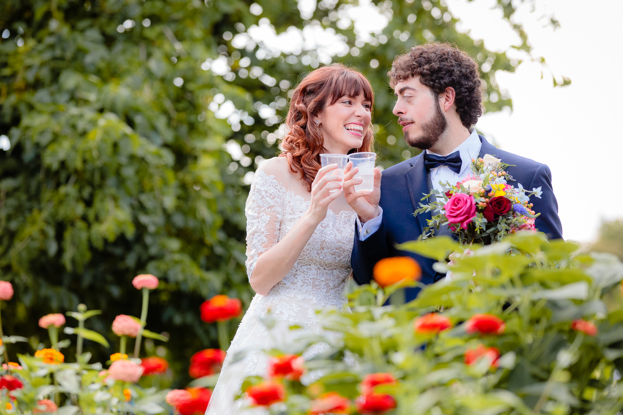 Newlyweds take a water break during portraits in the flower beds at Beaver Station