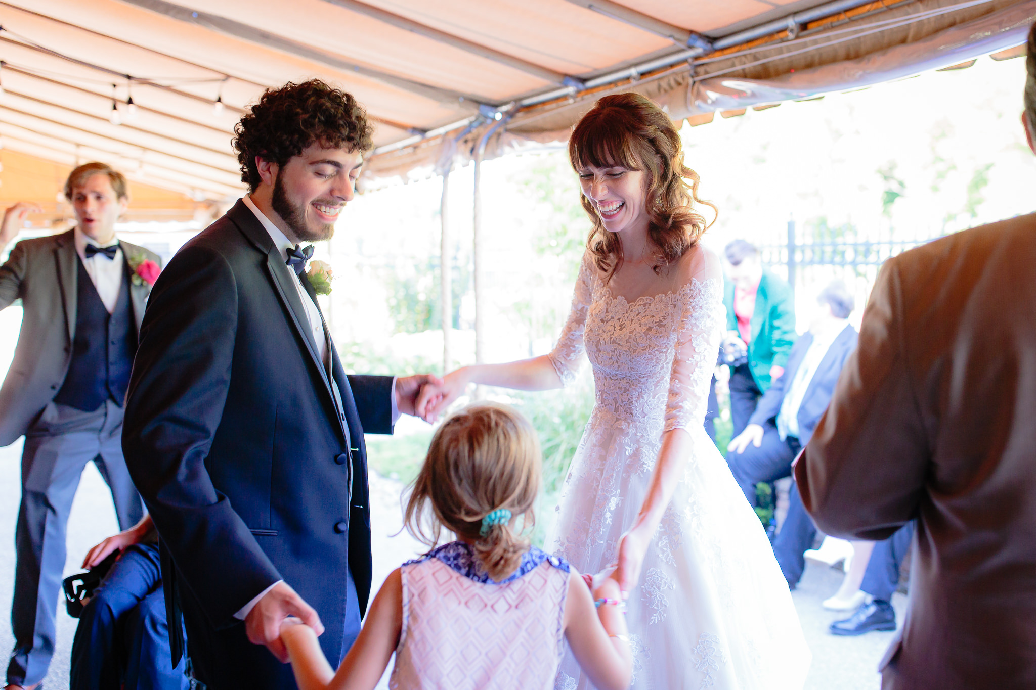 Bride & groom dance with a young guest at their Beaver Station wedding