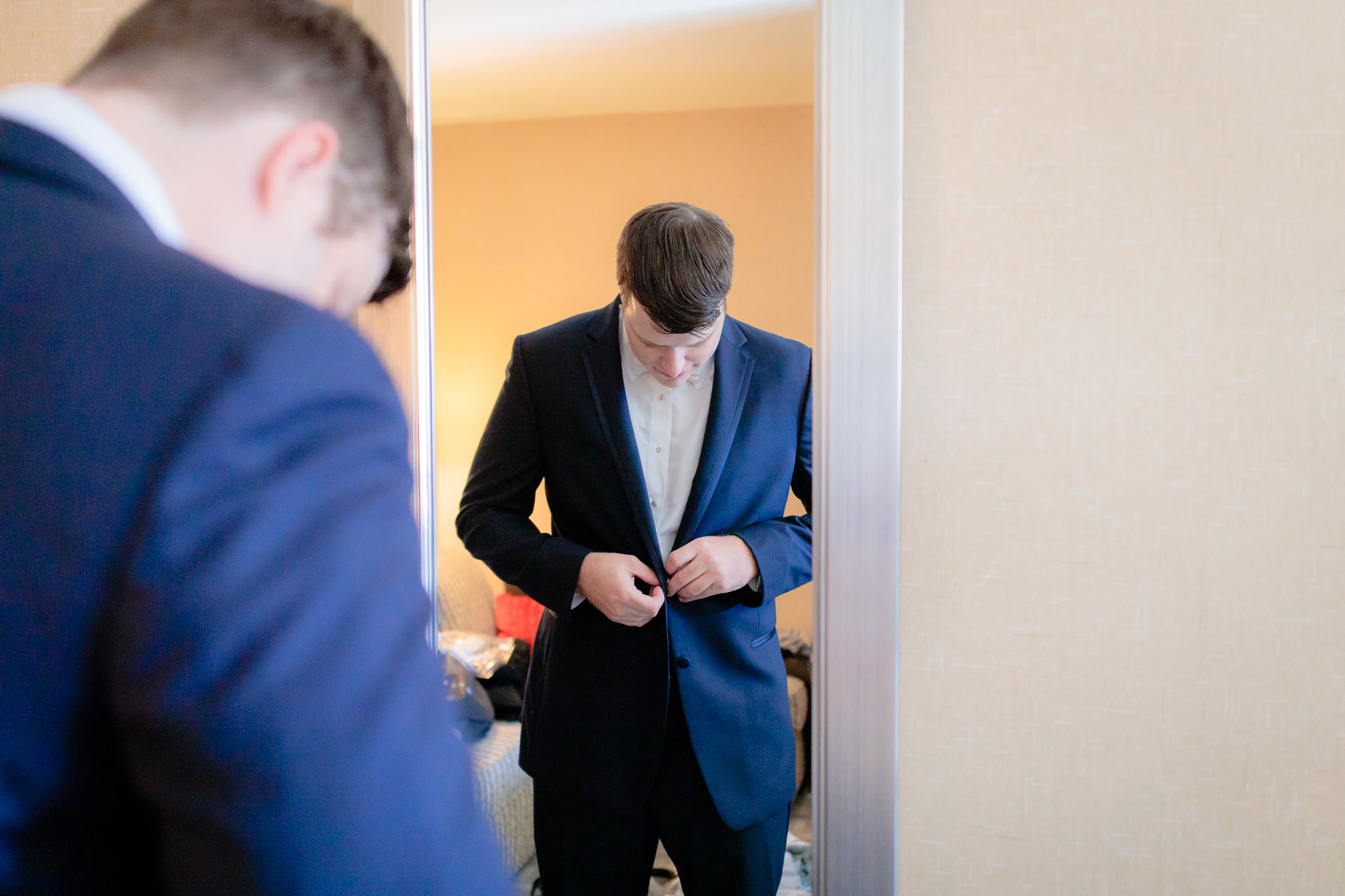 Groom buttons his blue tuxedo jacket at Cambria Hotel in downtown Pittsburgh