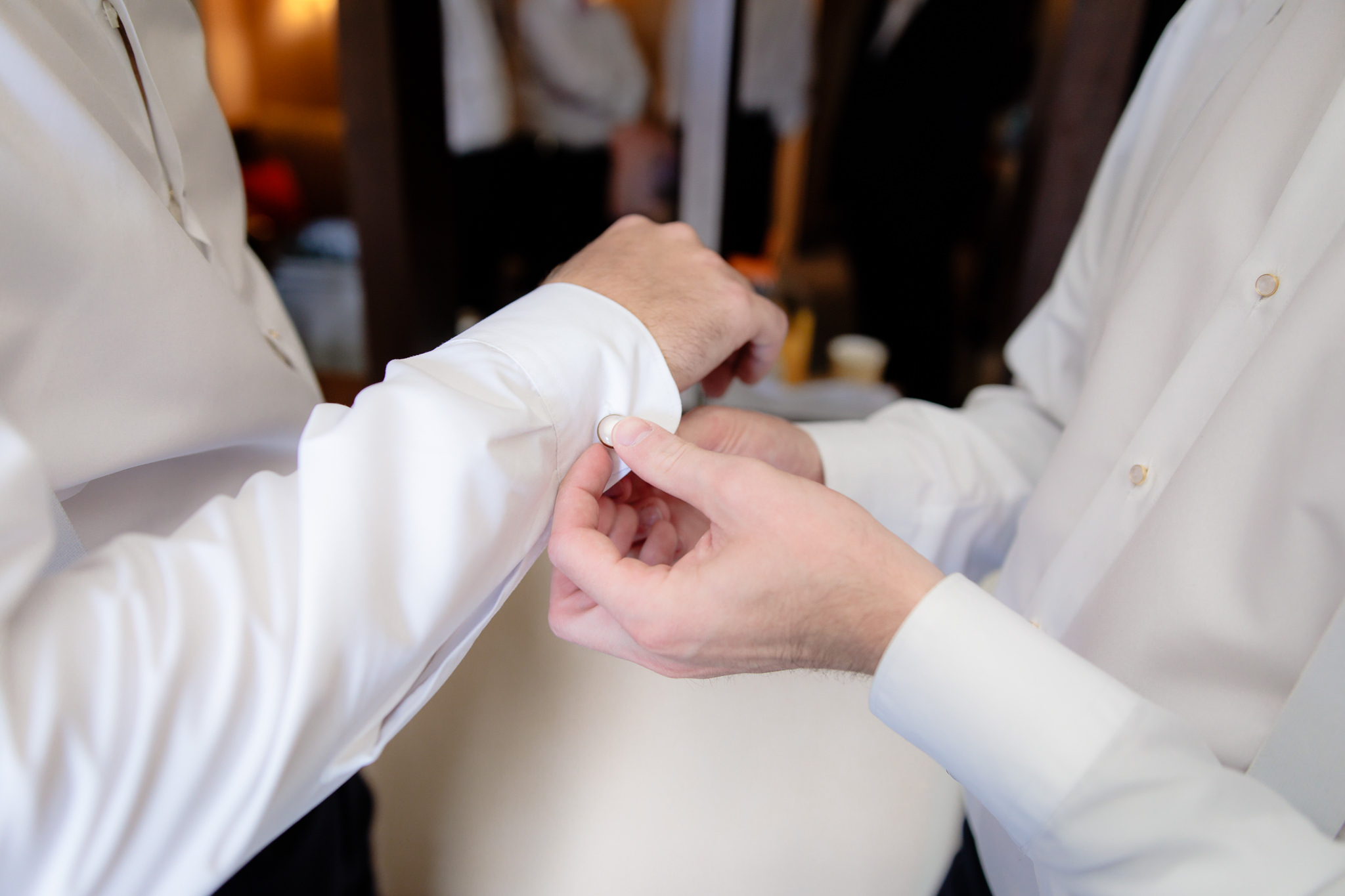 Groomsman fastens groom's cufflinks before his wedding at Duquesne University