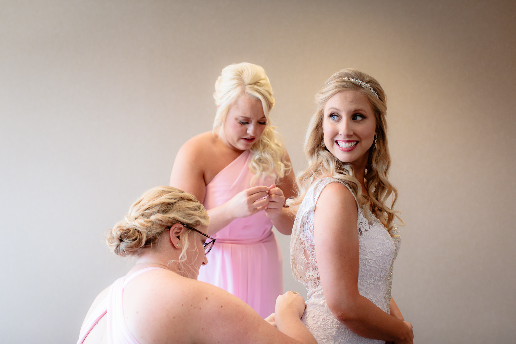Bride smiles as bridesmaids help her into her dress at Cambria Hotel in Pittsburgh