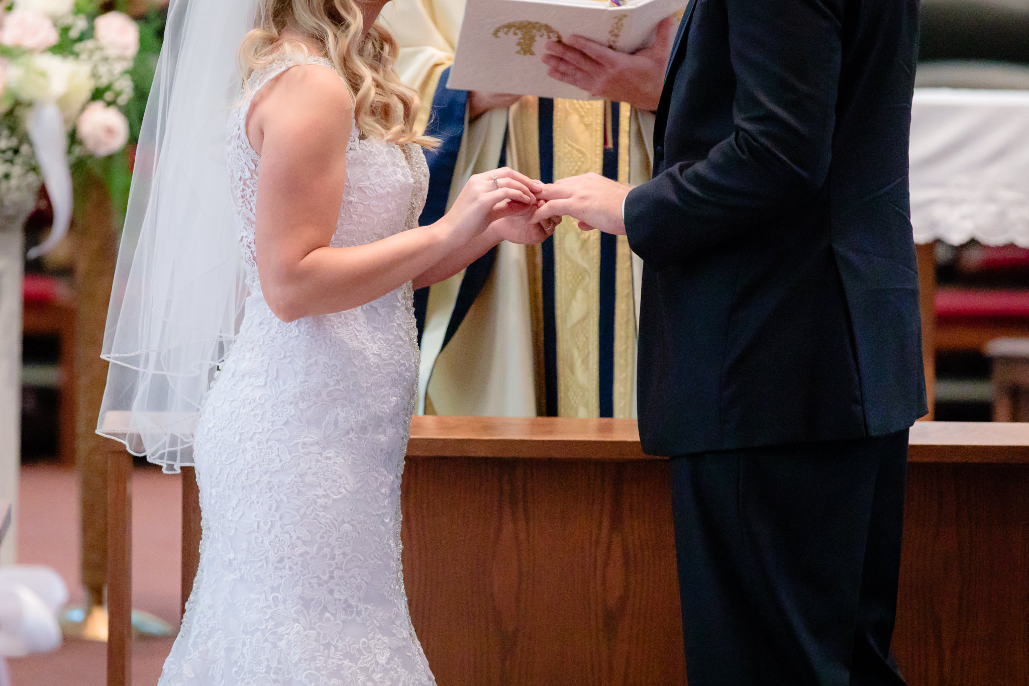 Bride puts groom's wedding band on his finger at Duquesne University Chapel of the Holy Spirit