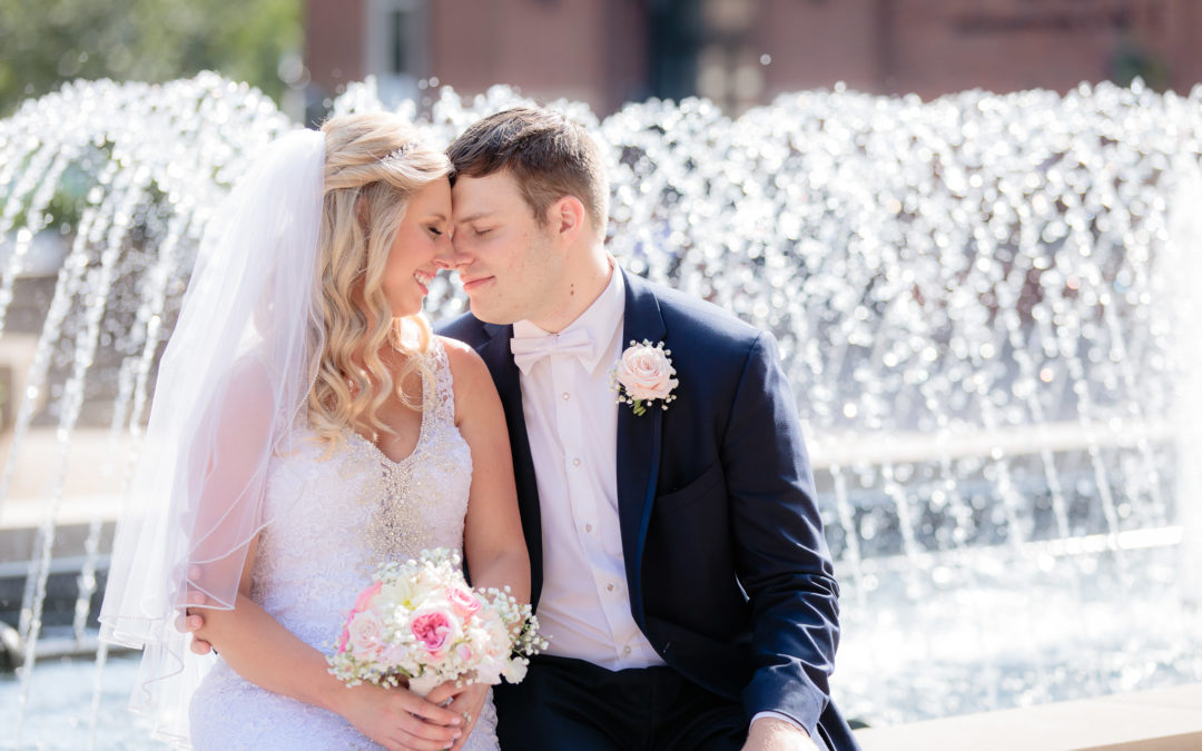 Newlyweds sit on a fountain at a wedding at Duquesne University