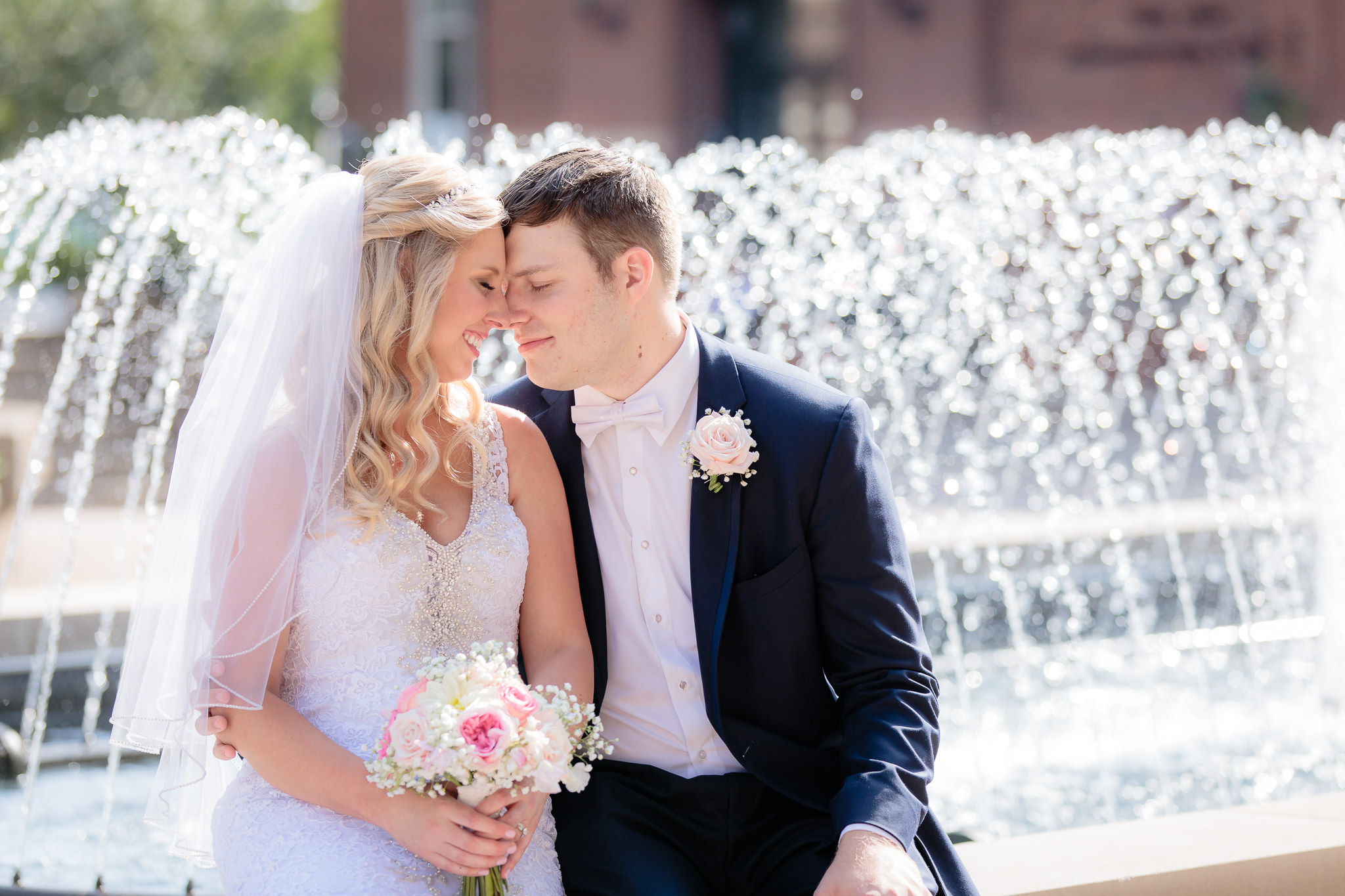 Newlyweds sit on a fountain at a wedding at Duquesne University